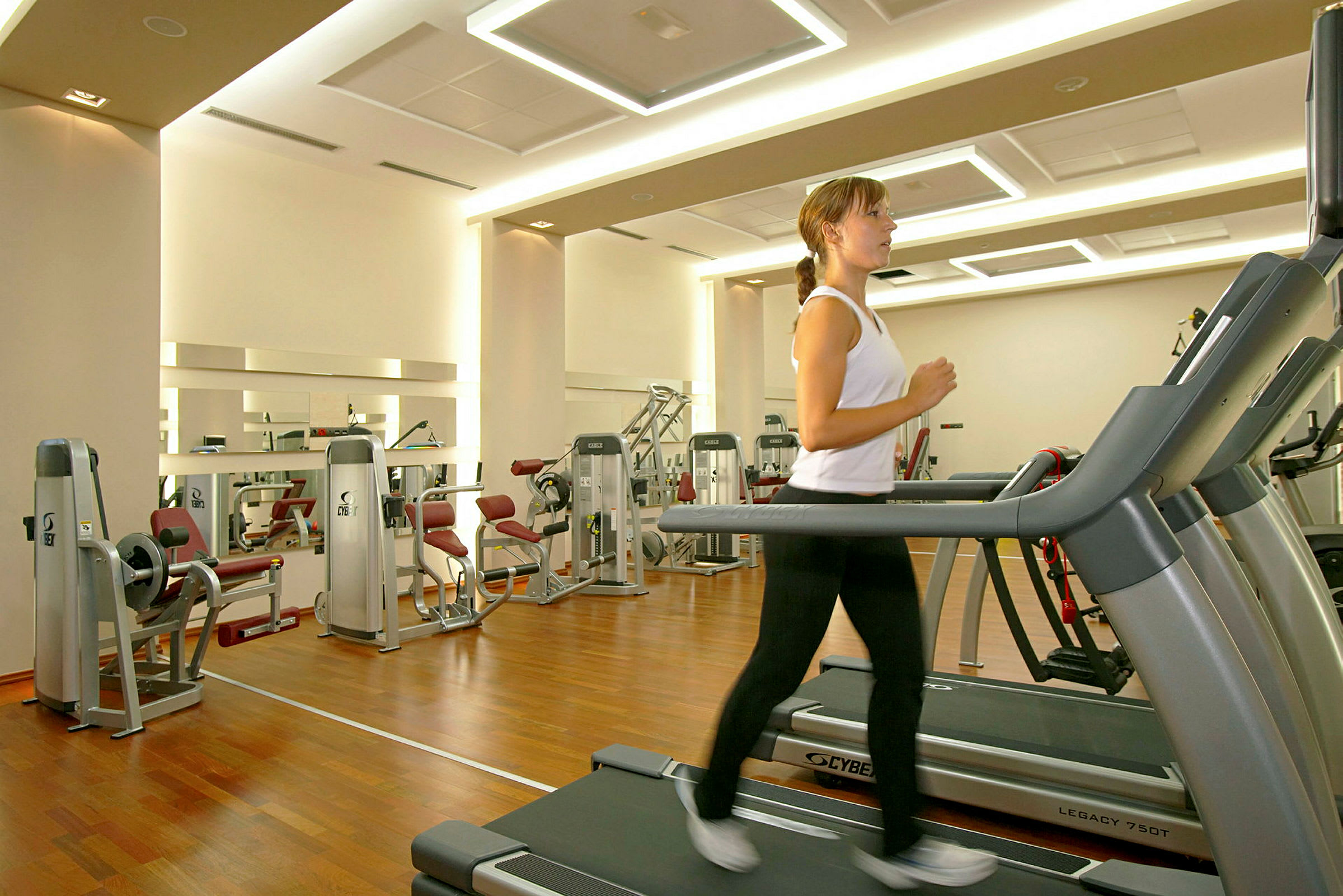 Fitnesscenter med træningsudstyr og en person, der løber på et løbebånd. (AI-genereret tekst)