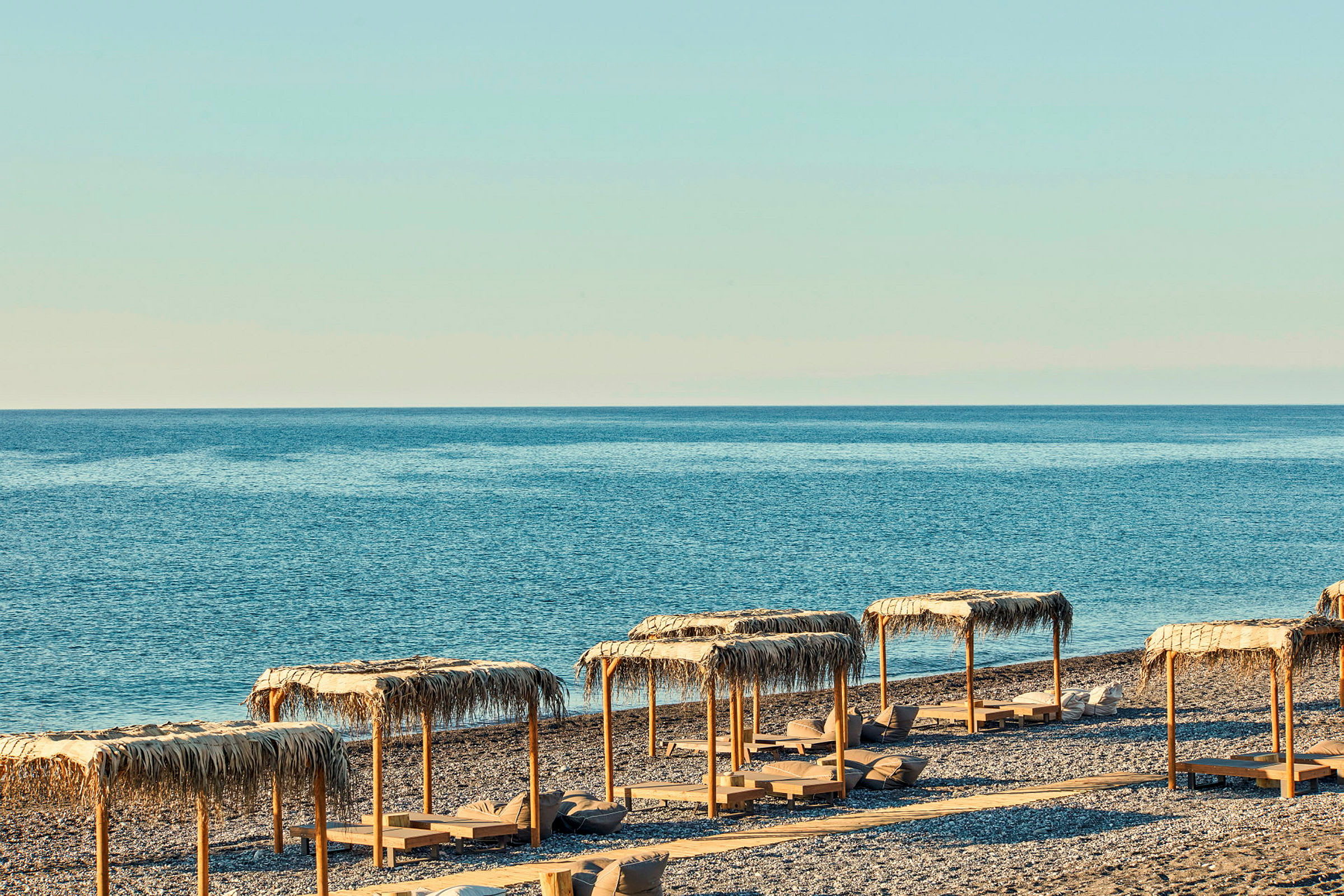Strand med parasoller og liggestole ved havet. (AI-genereret tekst)