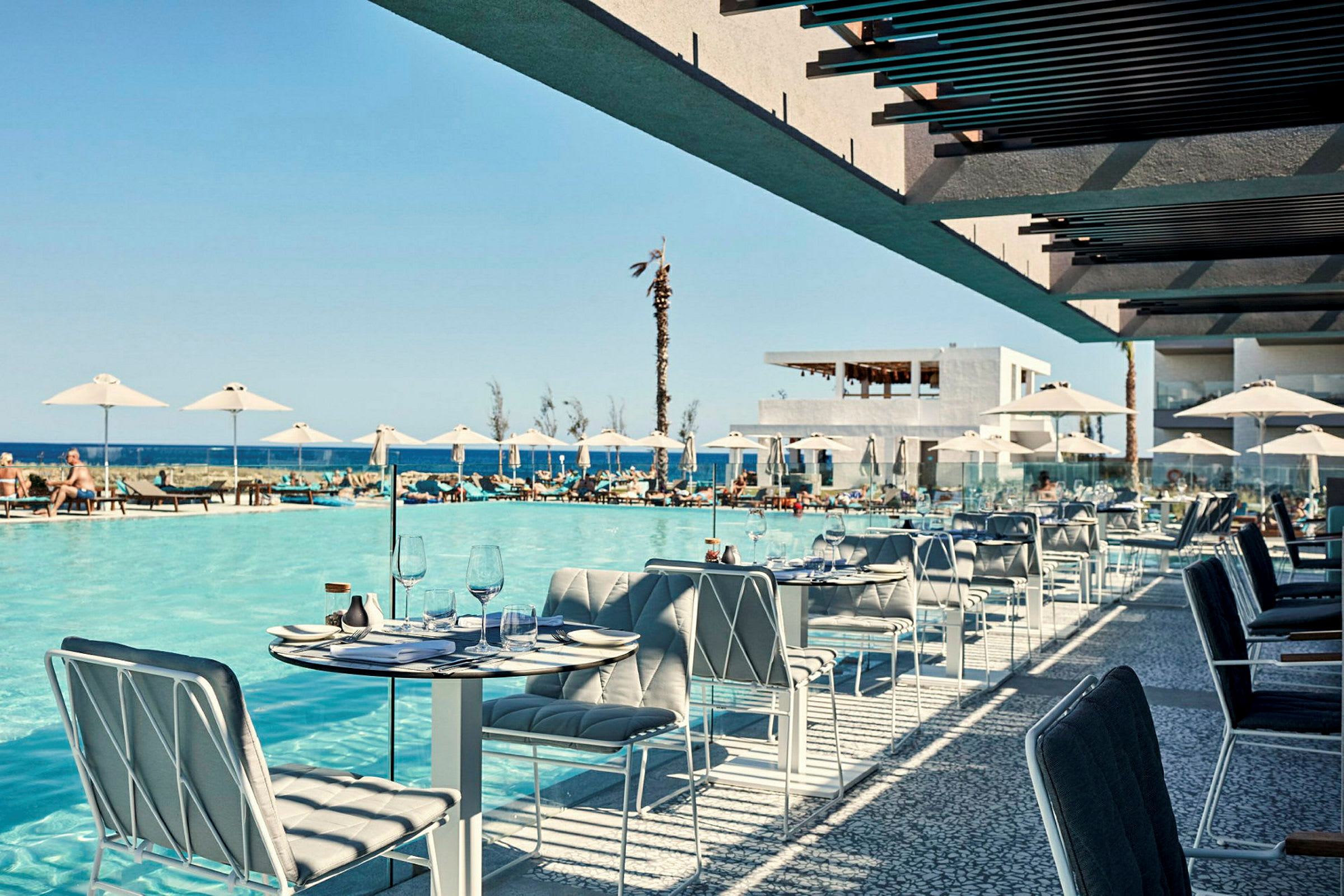 Udendørs servering med udsigt til en pool og havet i baggrunden. (AI-genereret tekst)