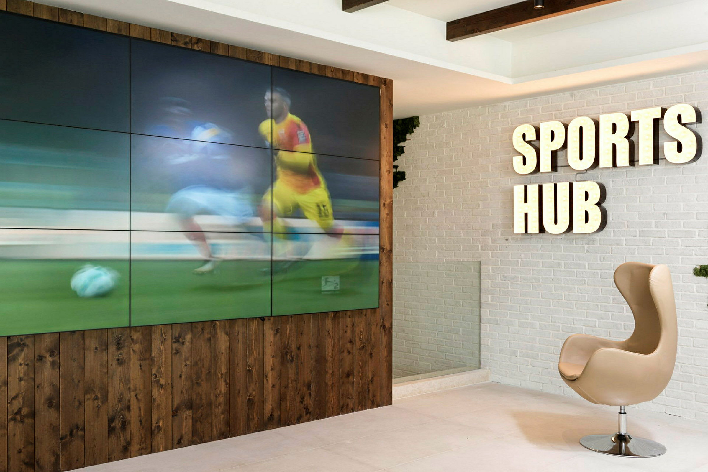 Interiør med skilt, der siger 'Sports Hub', og en skærm, der viser sport. (AI-genereret tekst)