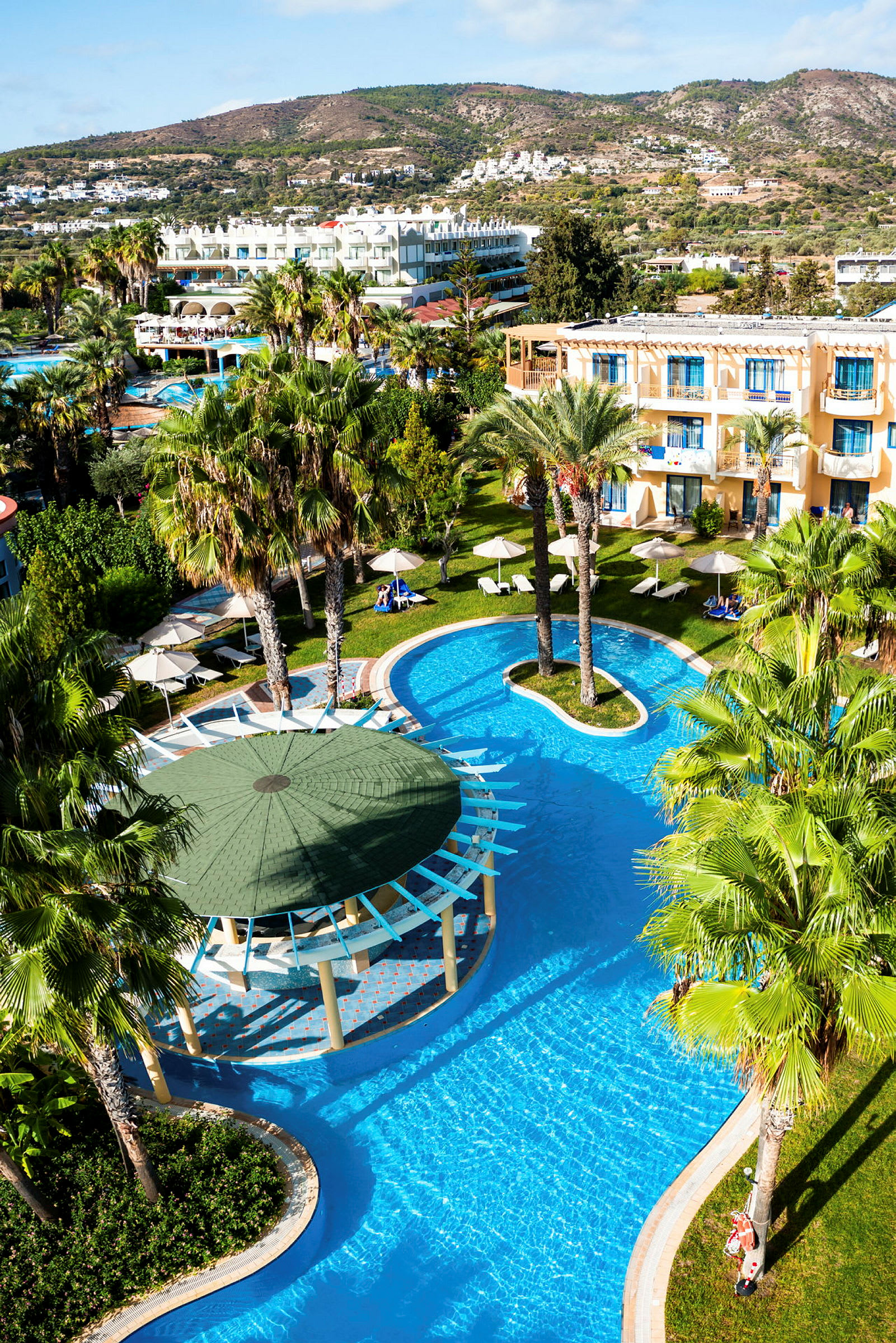 Hotelområde med pools, palmer og bygninger i baggrunden. (AI-genereret tekst)