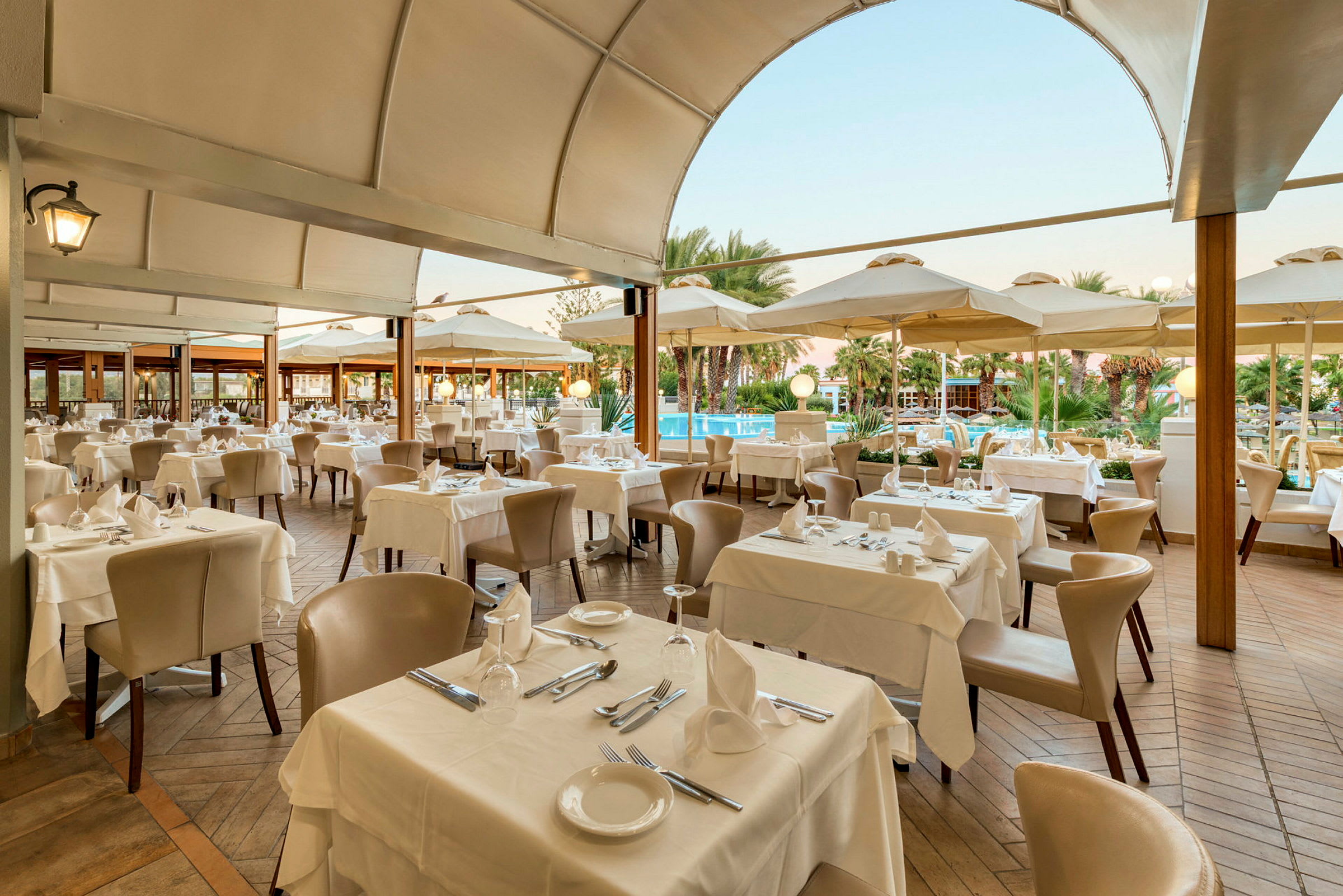 Restaurant med dækkede borde og stole under en overdækket terrasse. (AI-genereret tekst)