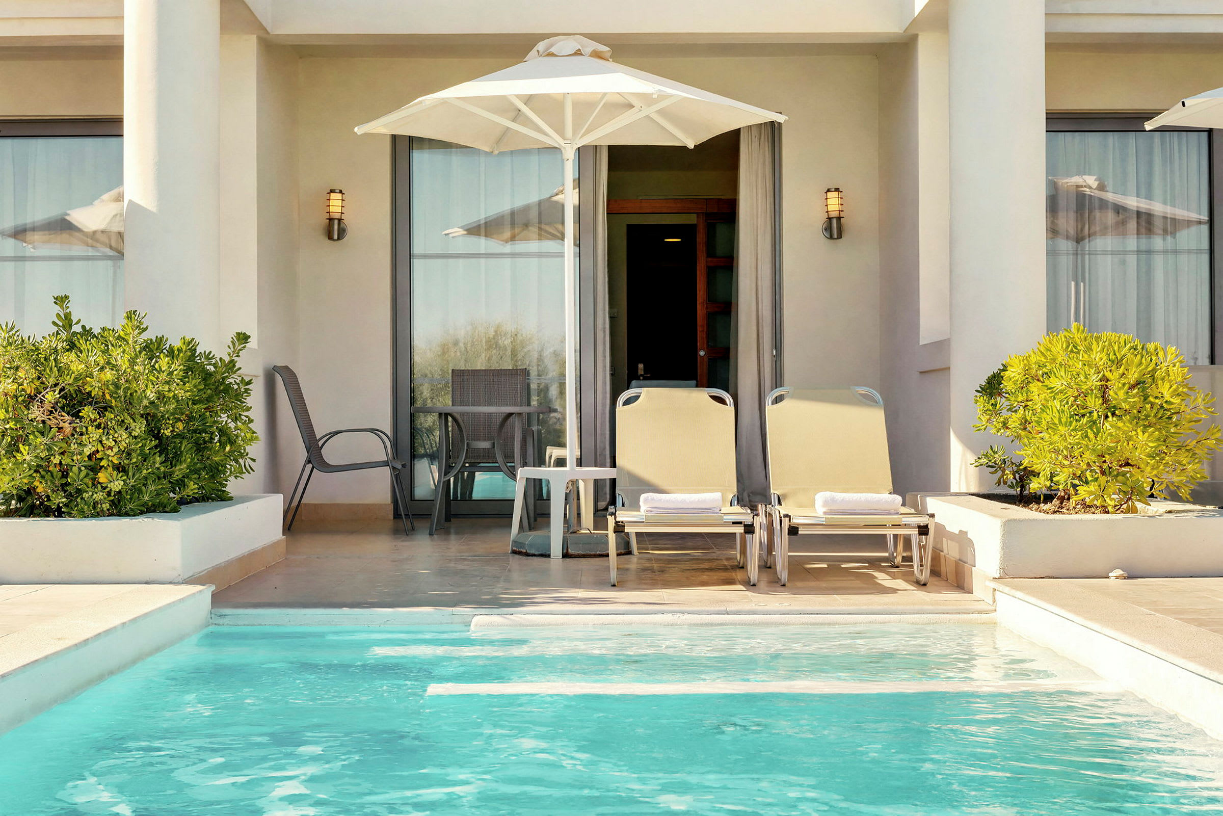 En privat terrasse med liggestole, parasol og en lille pool. (AI-genereret tekst)