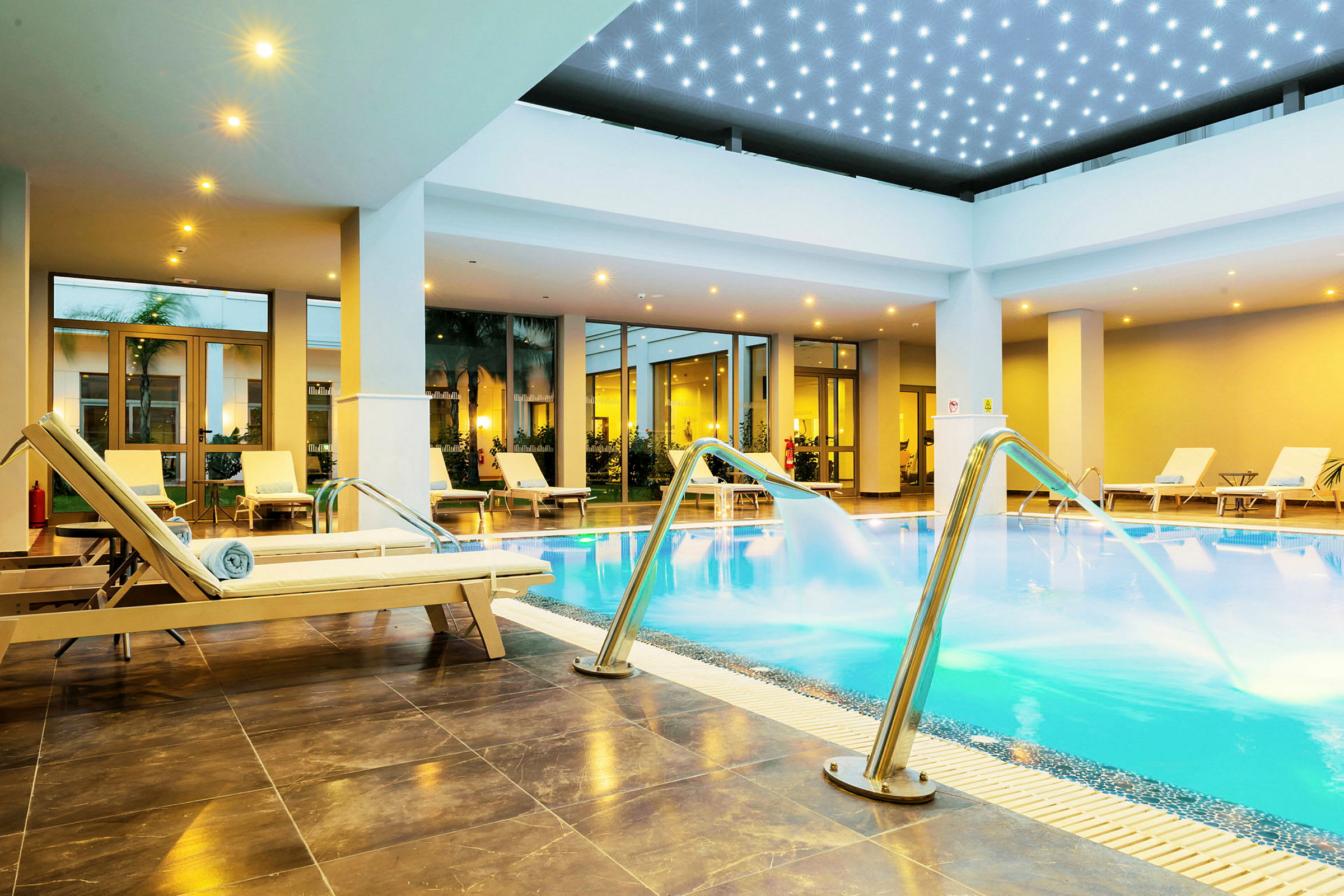 Indendørs pool med liggestole og vandstråler. (AI-genereret tekst)
