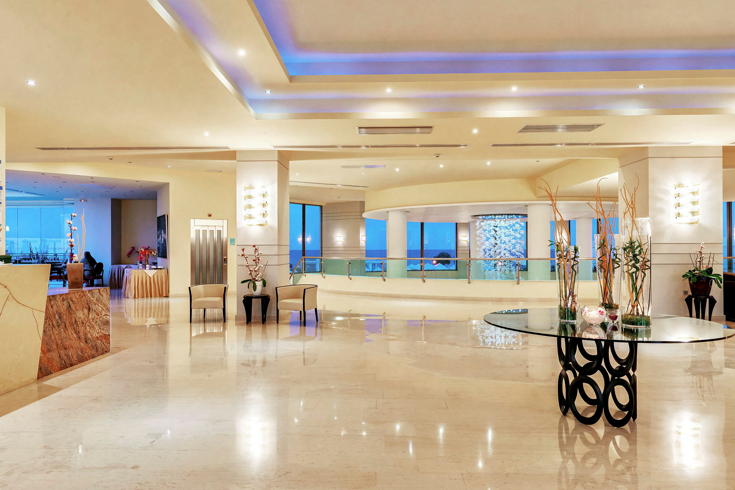 En rummelig hotelreception med moderne indretning, glasbord og dekorationer. (AI-genereret tekst)