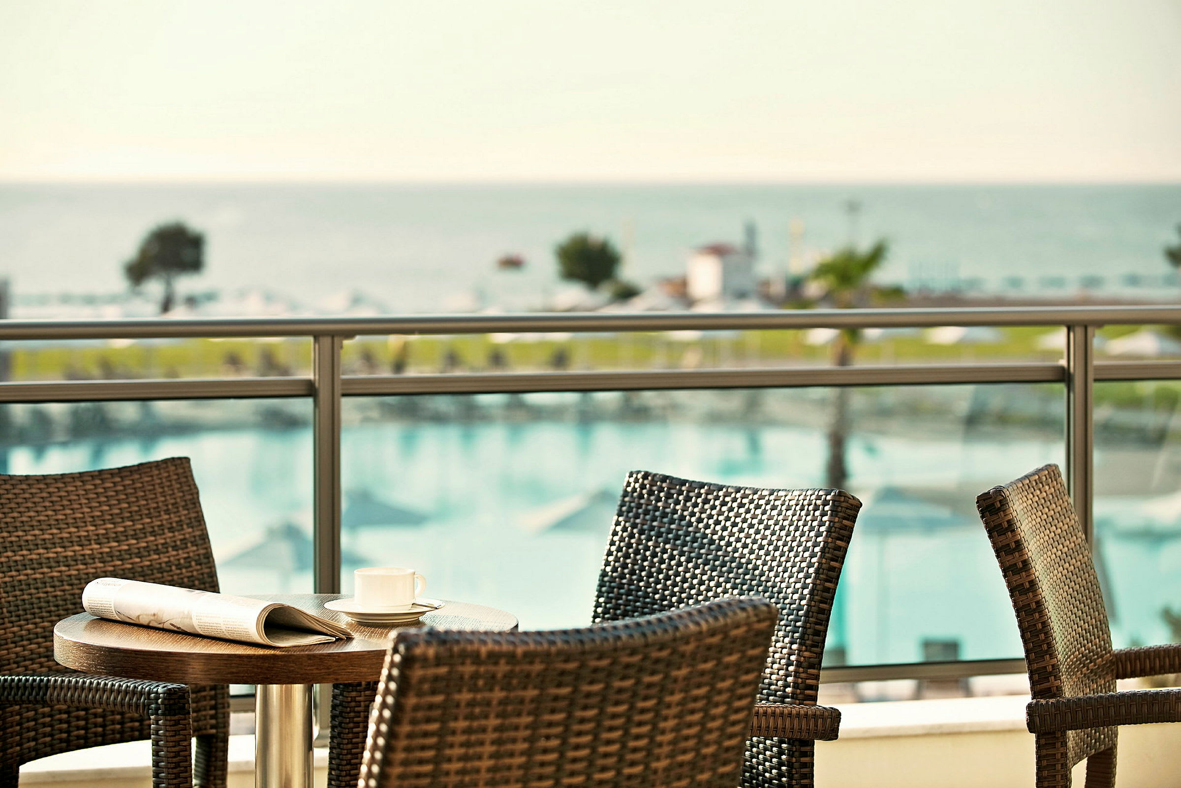 Terrasse med fletmøbler og udsigt over pool og hav. (AI-genereret tekst)