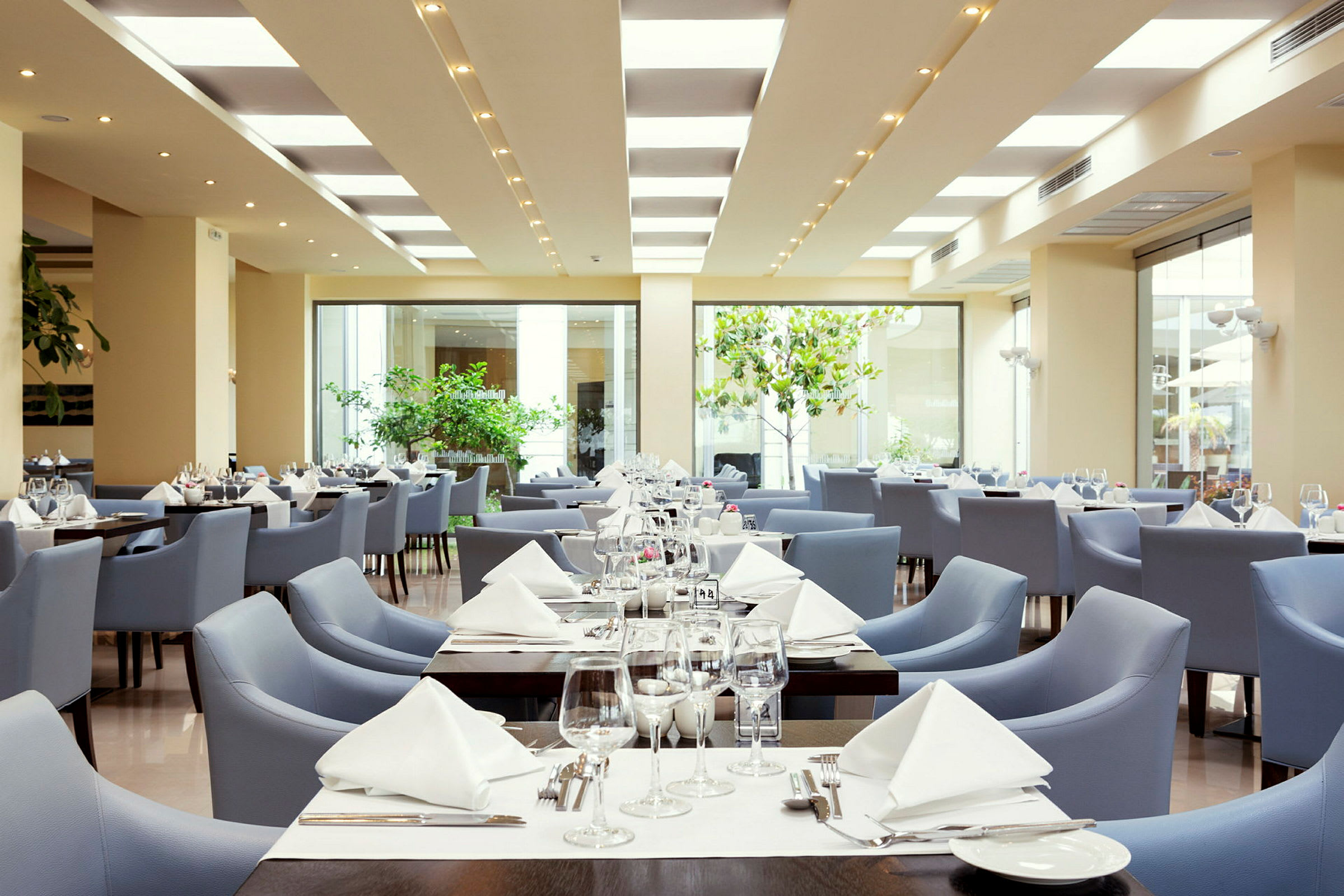 Billede af en moderne restaurant med borde dækket og blå stole. (AI-genereret tekst)