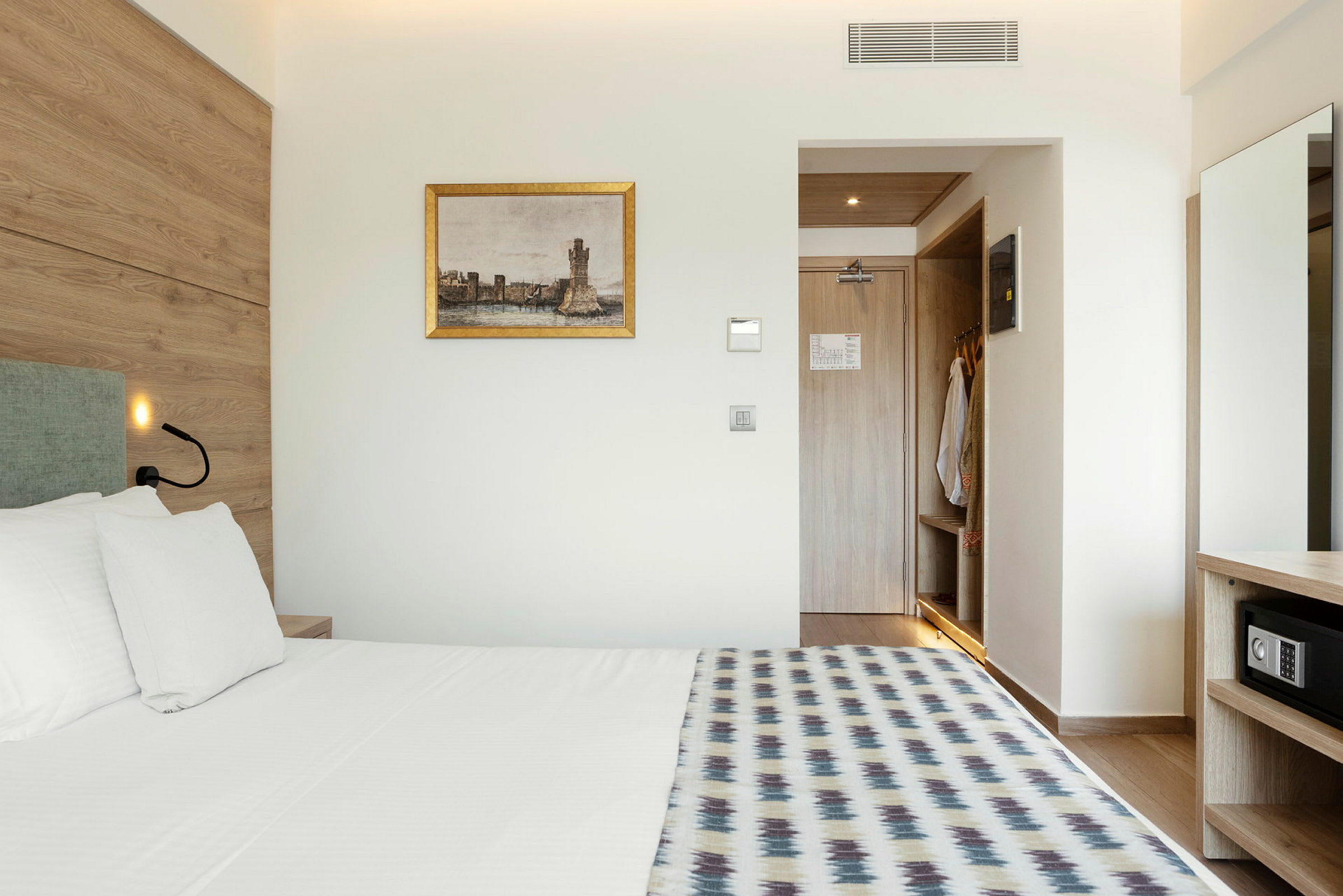 Et hotelværelse med seng, vægmaleri og en åben garderobe. (AI-genereret tekst)