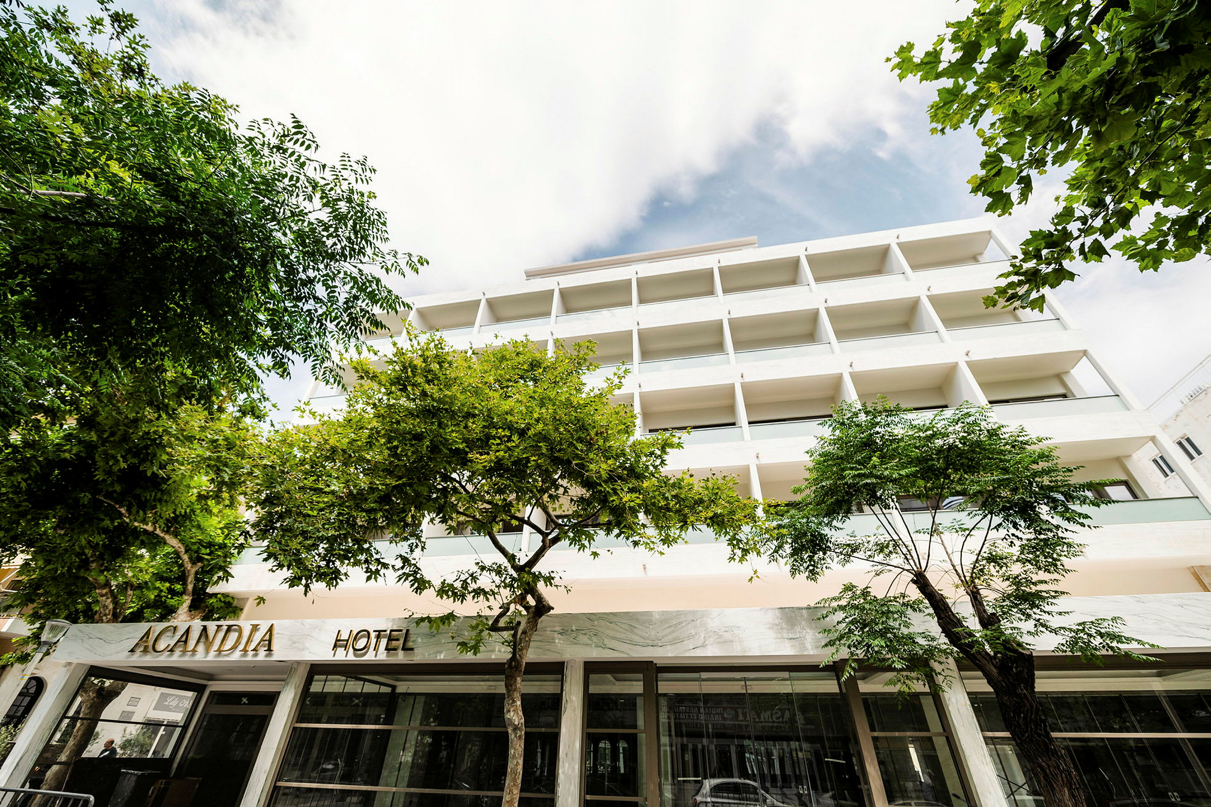 Billede af hotellet Acandia med facaden og omkringliggende træer. (AI-genereret tekst)