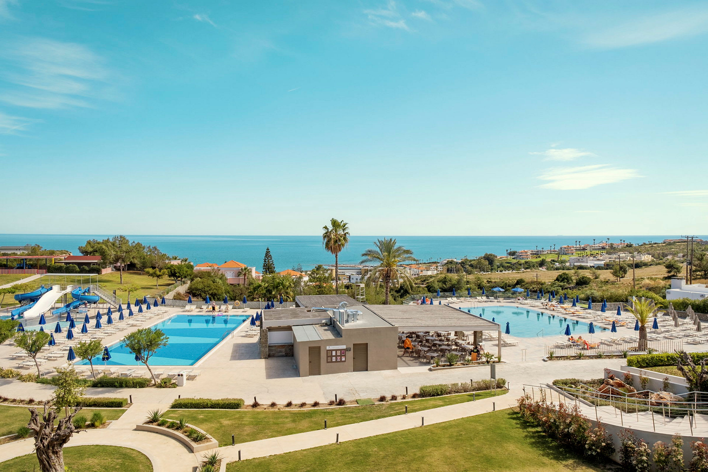 Hotelområde med to swimmingpools, liggestole og havudsigt. (AI-genereret tekst)