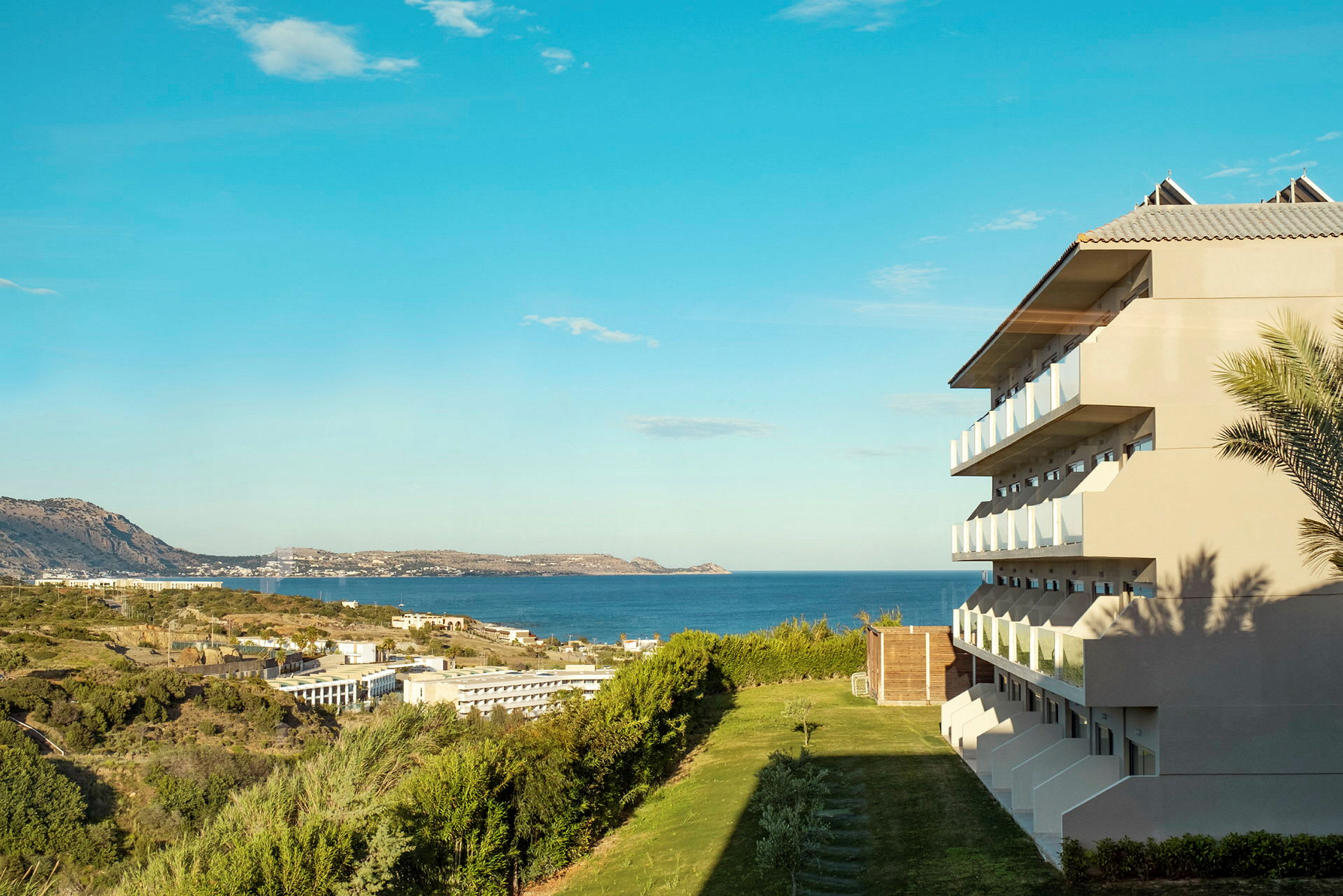 Billede af et hotel med altaner med udsigt over havet og grønne områder. (AI-genereret tekst)