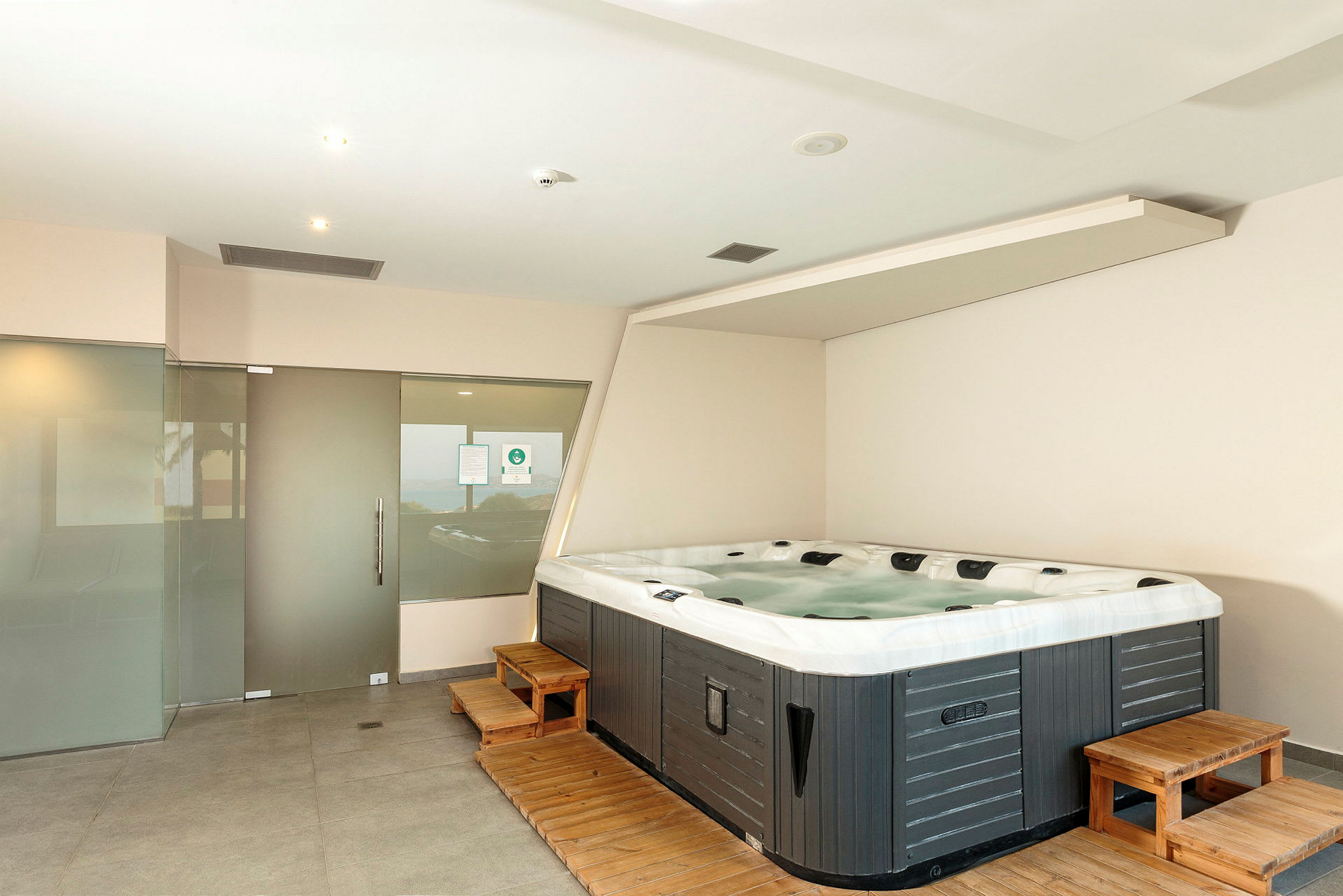 Et rum med en jacuzzi og glasdøre. (AI-genereret tekst)