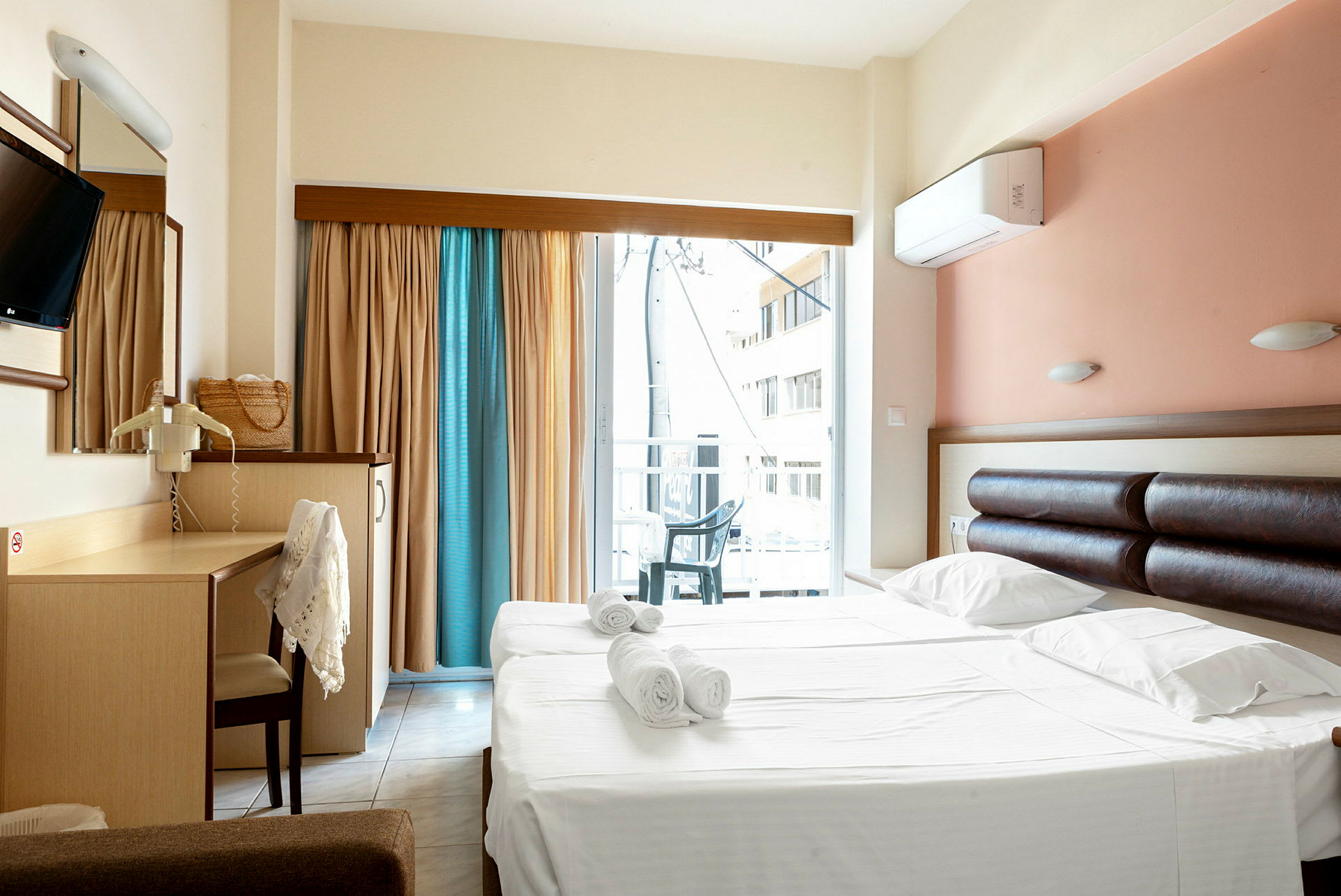 Hotelværelse med dobbeltseng og skrivebord samt balkon med udsigt. (AI-genereret tekst)