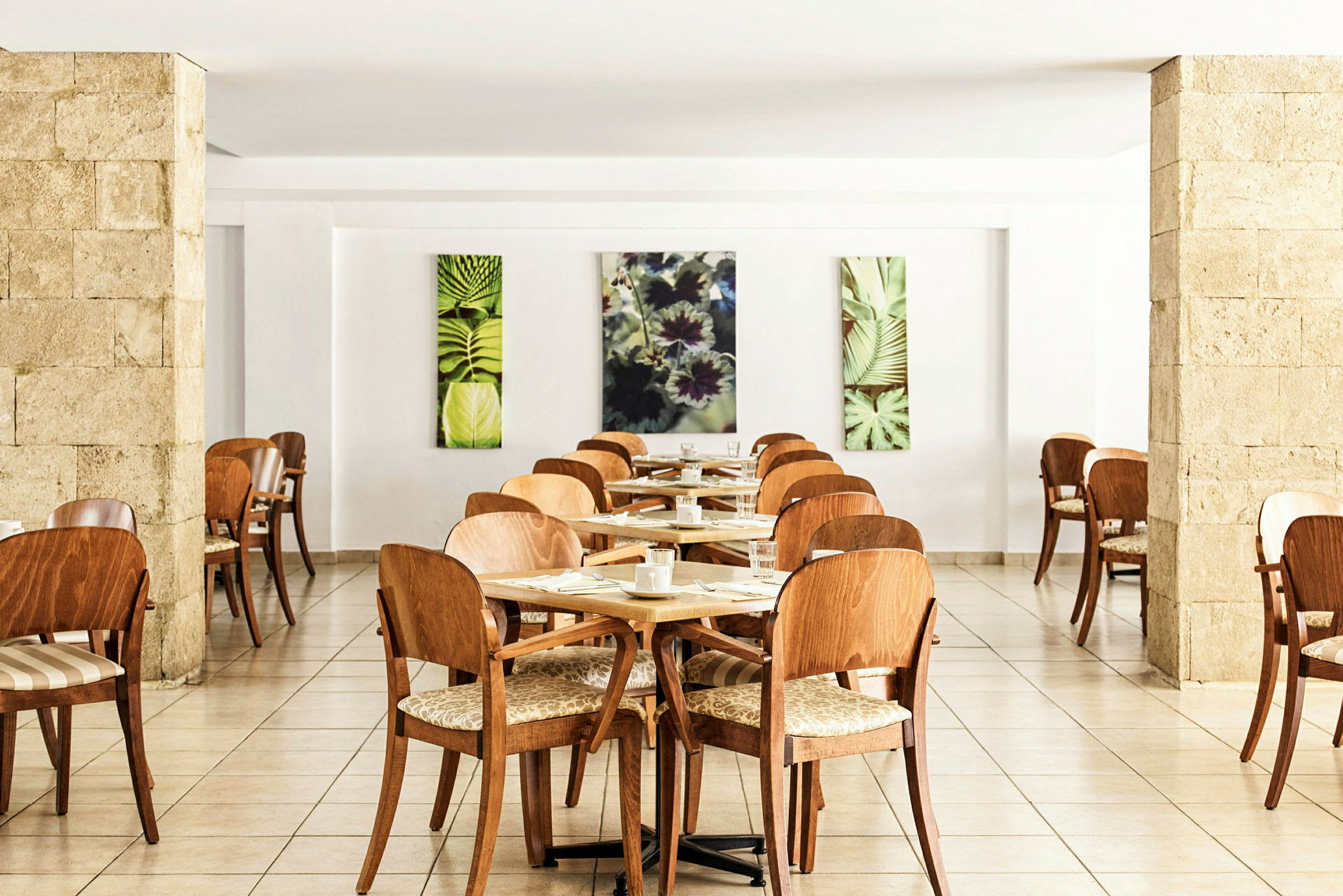 Restaurant med træstole og borde, dekoreret med kunstværker med plantemotiver. (AI-genereret tekst)