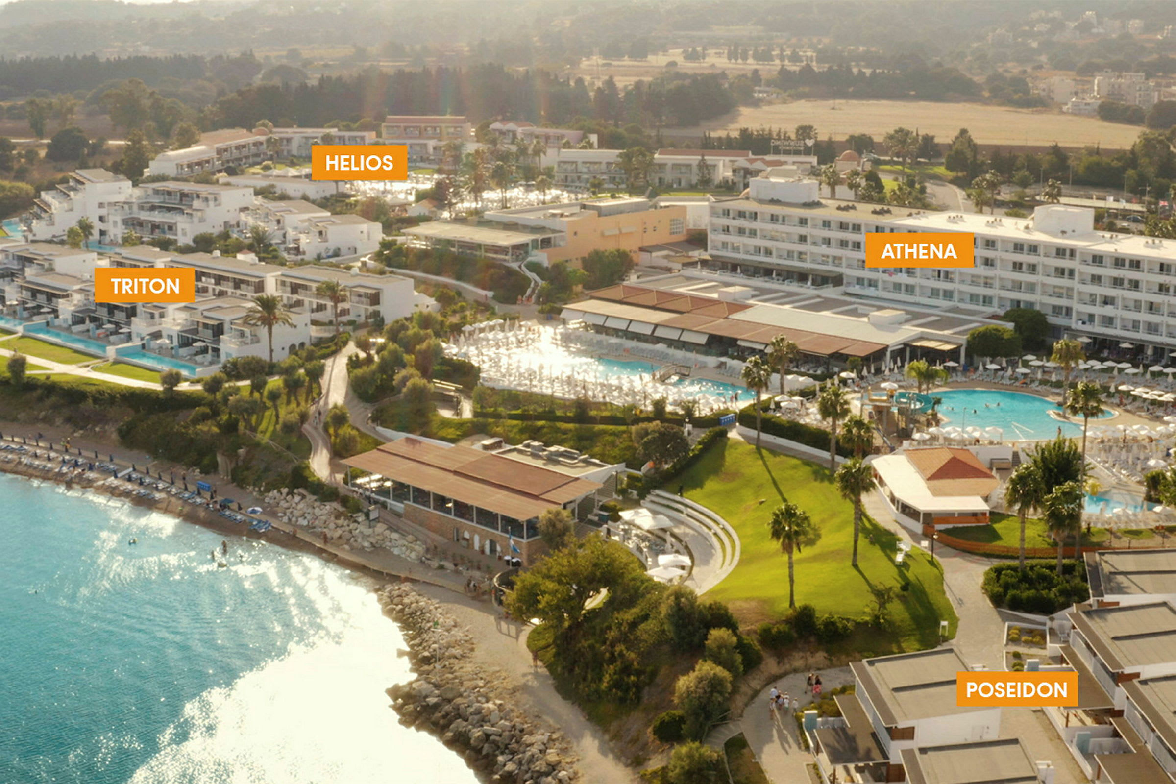 Luftfoto af resort med flere hotelbygninger og en pool nær en strand. (AI-genereret tekst)