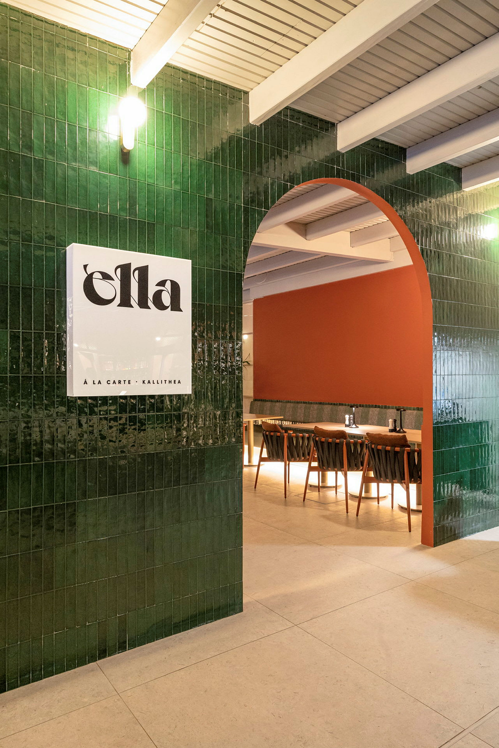 En indbydende restaurantinteriør med en grøn flisebelagt bue, en orangefarvet væg og siddepladser. (AI-genereret tekst)