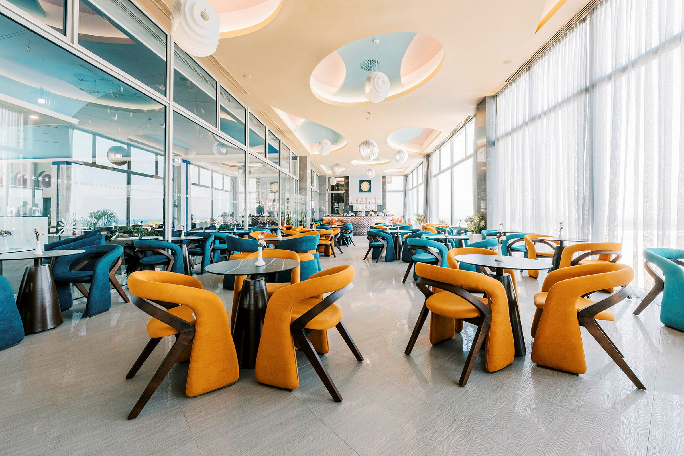En moderne restaurant med farverige stole og store vinduer. (AI-genereret tekst)