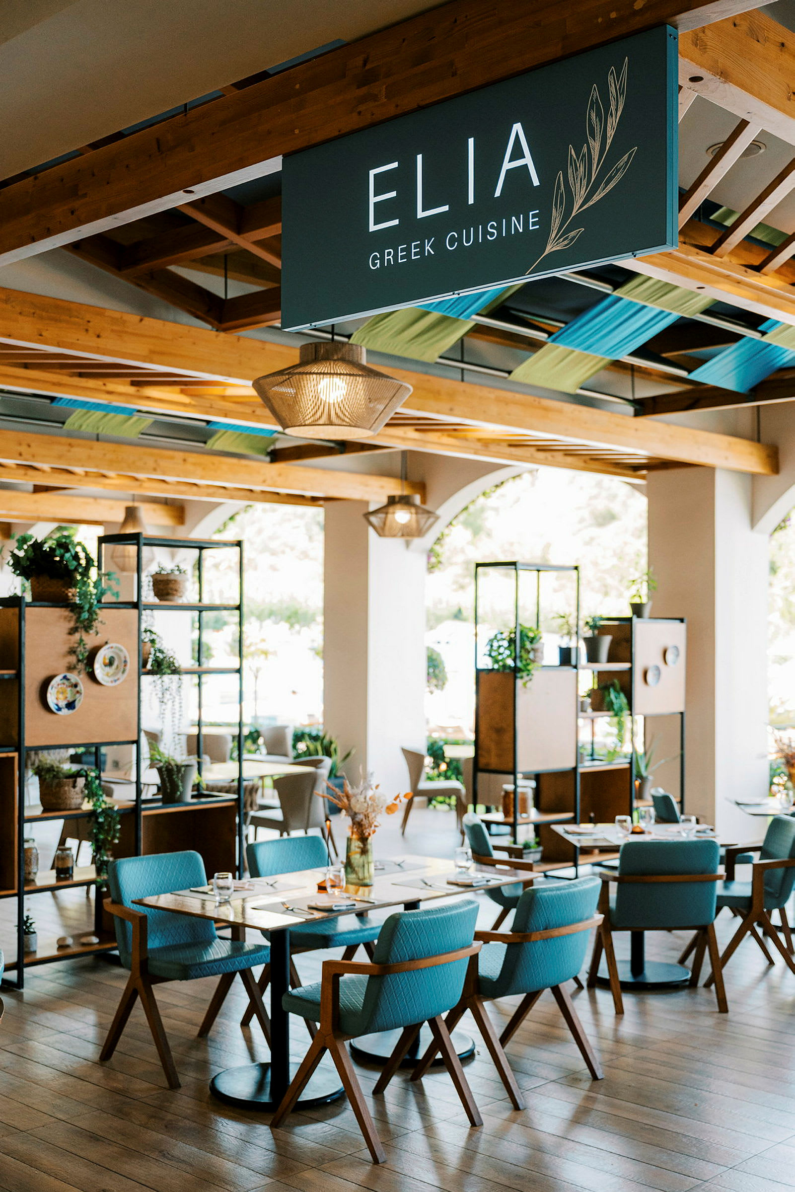 Et indbydende restaurantområde med moderne interiør, borde og stole samt grøn dekoration. (AI-genereret tekst)