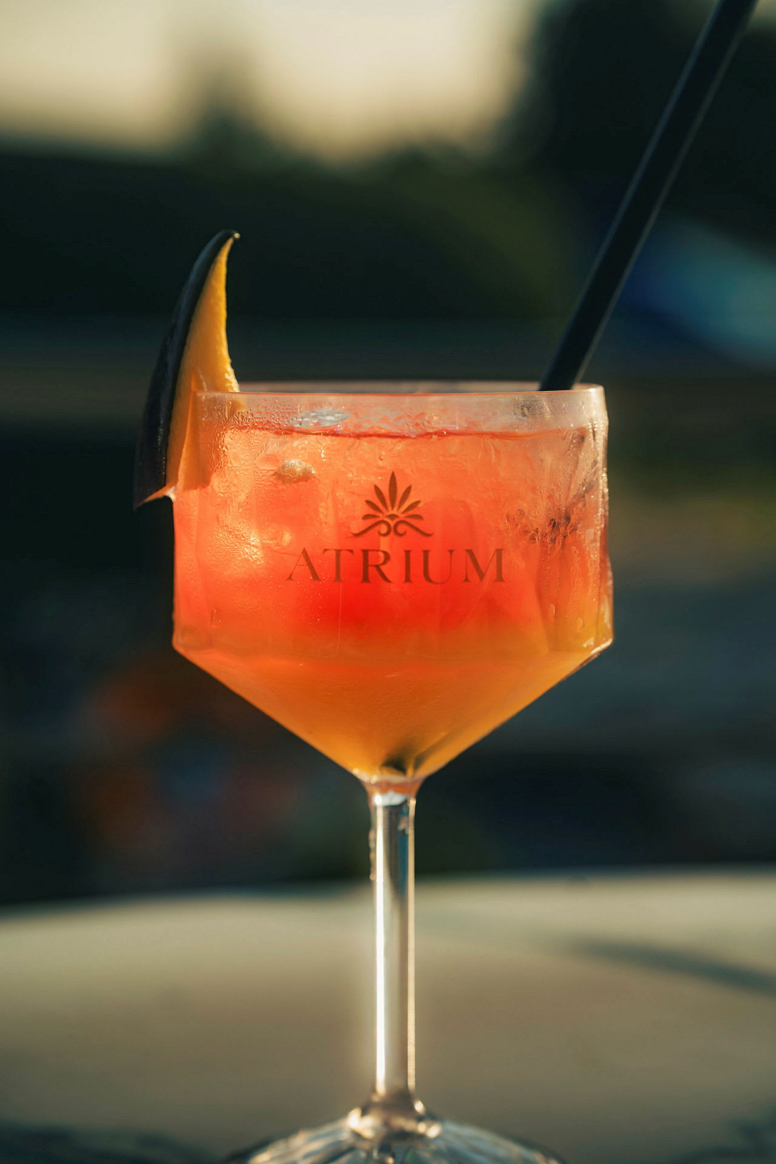 Et glas med en orangefarvet drink og isterninger, dekoreret med en skive citrusfrugt på kanten. (AI-genereret tekst)