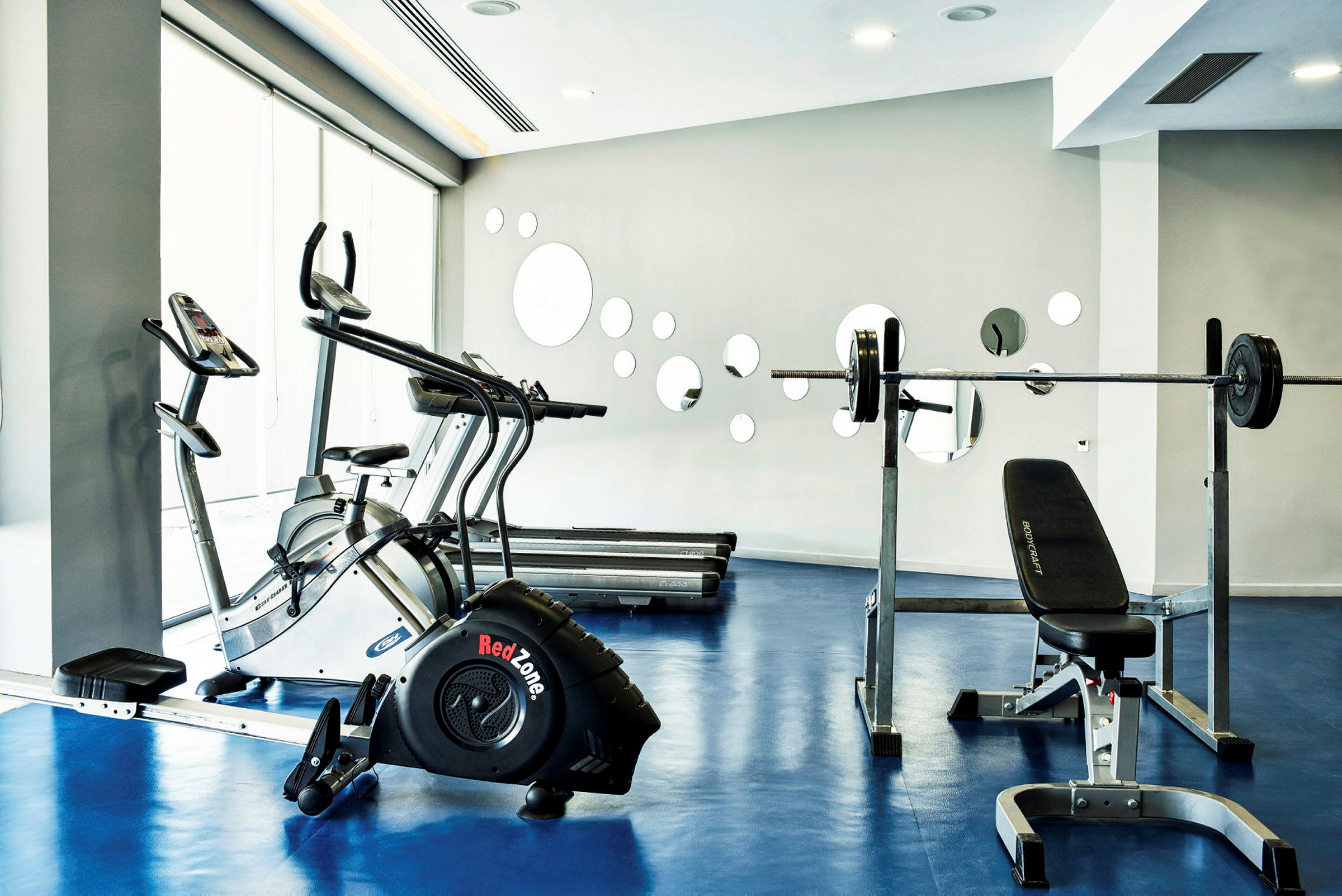 Fitnesscenter med træningsmaskiner som løbebånd og styrketræningsudstyr. (AI-genereret tekst)