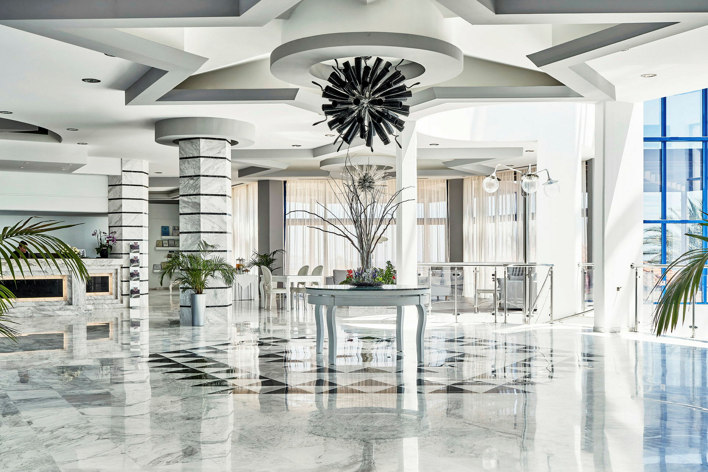 Interiør af en lys hotellobby med marmorgulv, dekorative søjler og moderne indretning. (AI-genereret tekst)