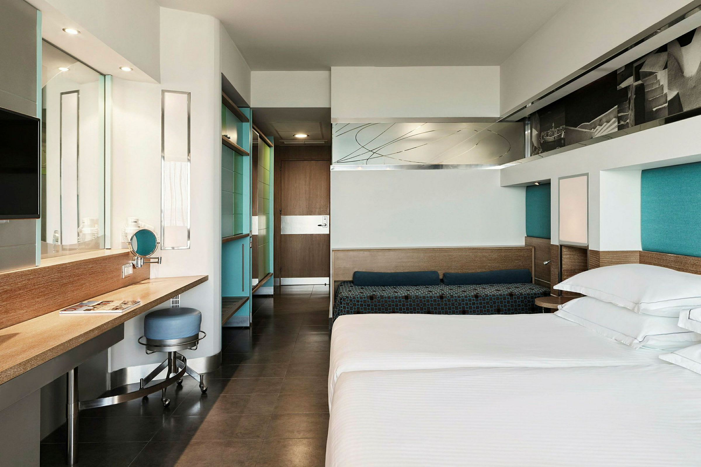 Et moderne hotelværelse med en seng, skrivebord og stol samt spejl og garderobe. (AI-genereret tekst)
