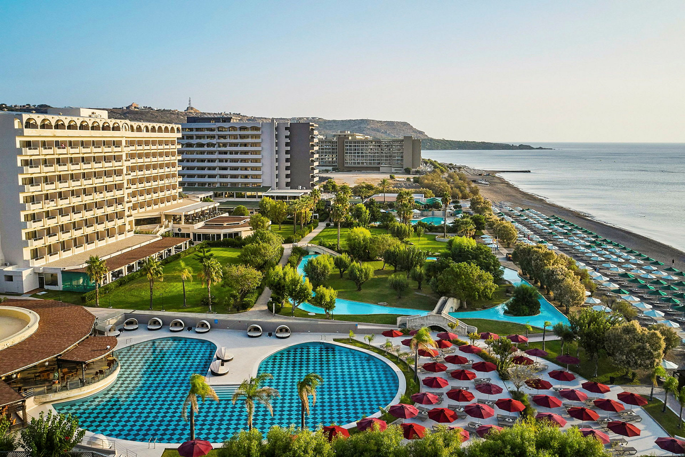 Hotelområde med pools, grønne områder og strand. (AI-genereret tekst)