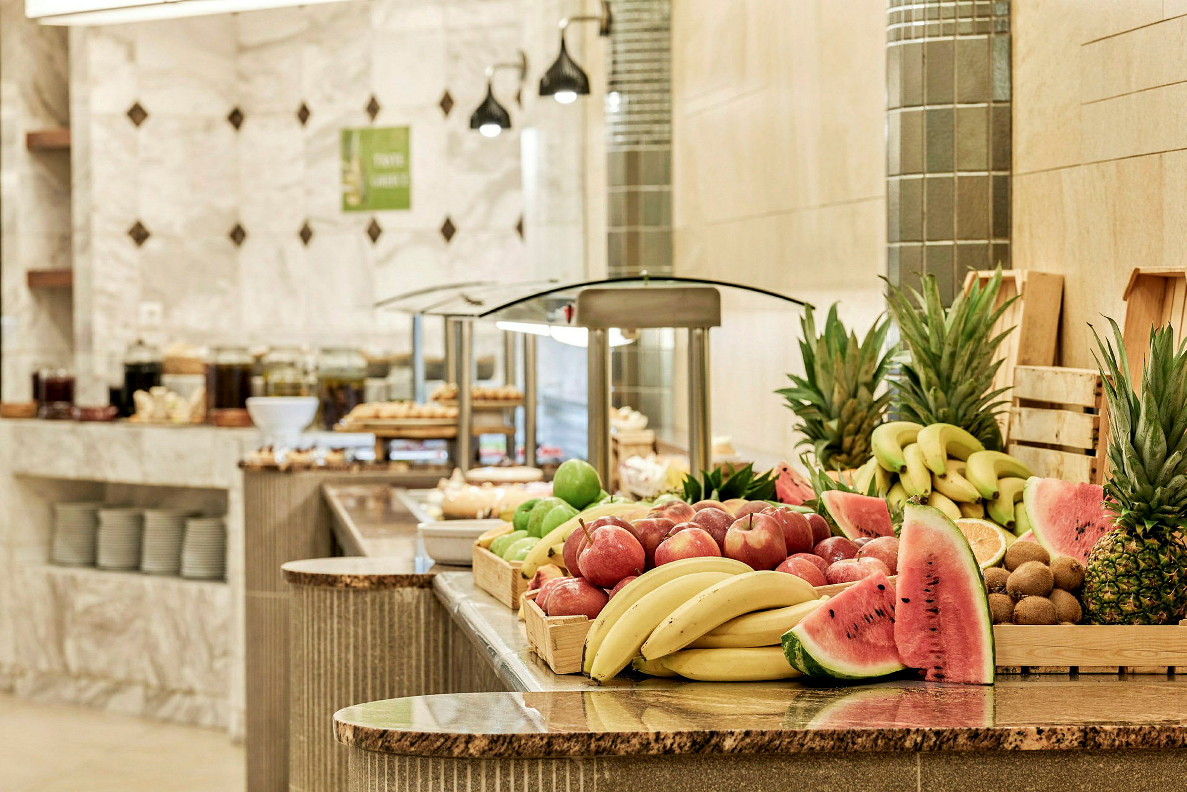 En buffet med frisk frugt inklusive bananer, æbler, ananas og vandmelon. (AI-genereret tekst)