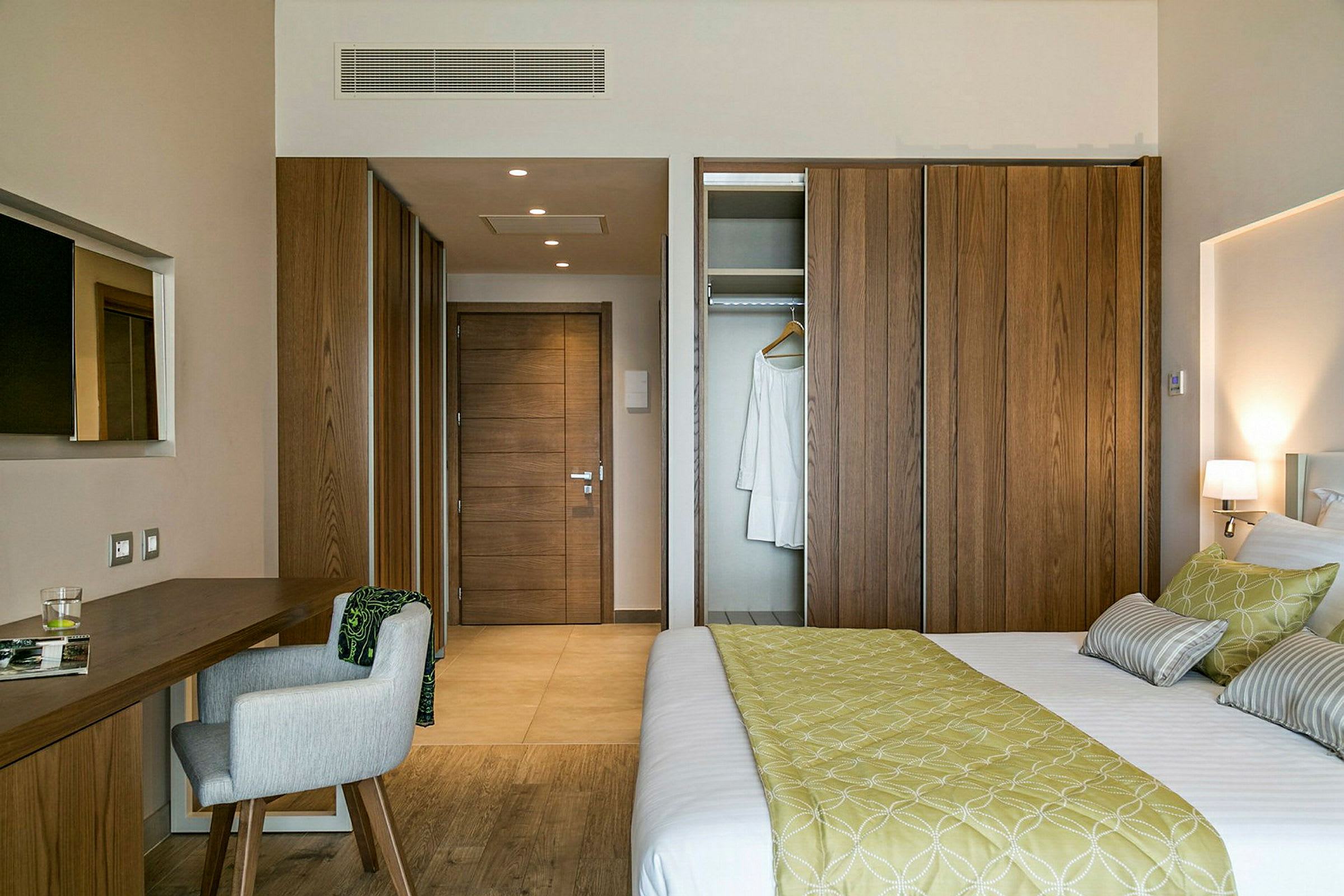 Et hotelværelse med en seng, et skrivebord med stol og garderobe. (AI-genereret tekst)