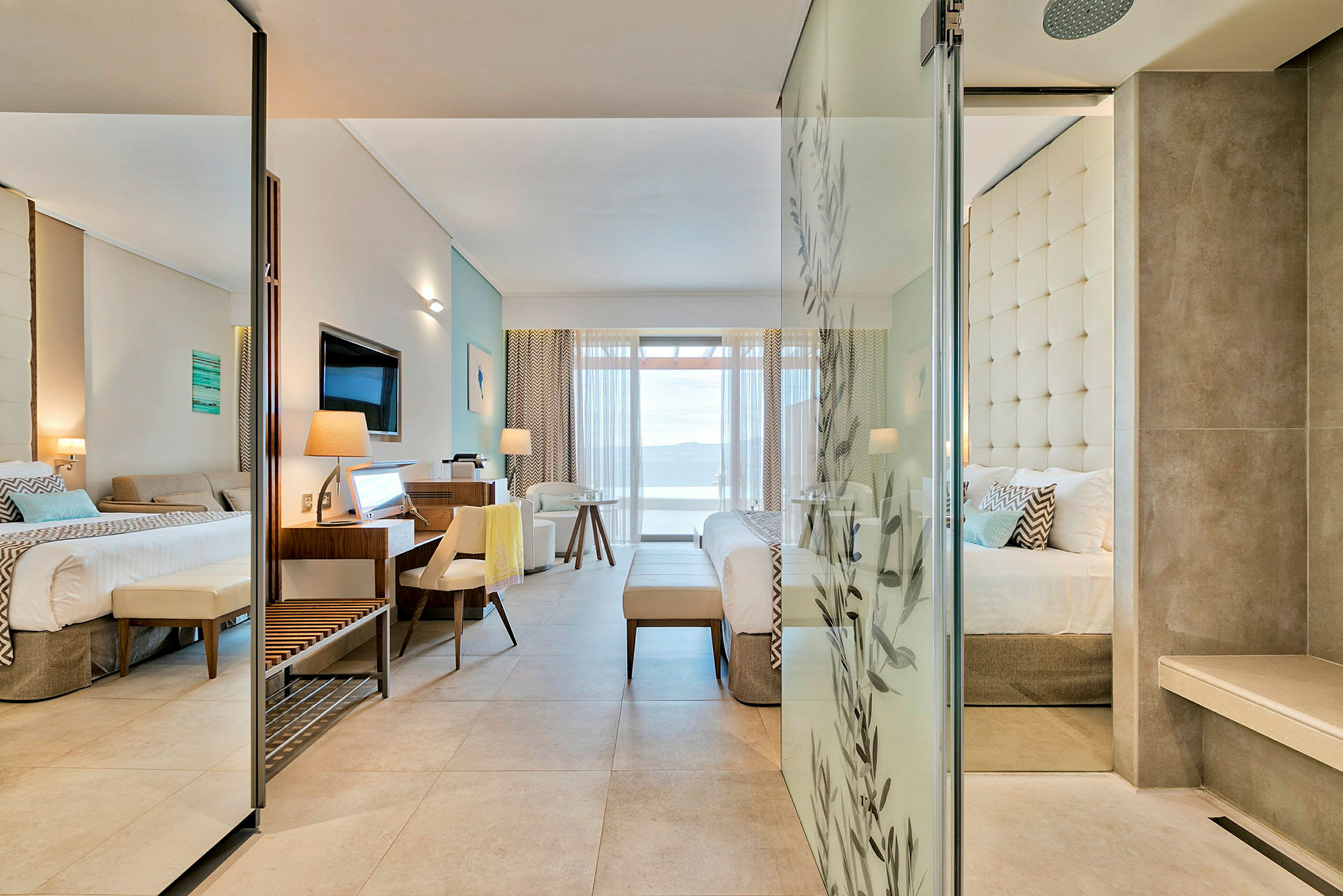 Et moderne hotelværelse med en dobbeltseng og siddeområde. Udenfor ses en balkon med havudsigt. (AI-genereret tekst)