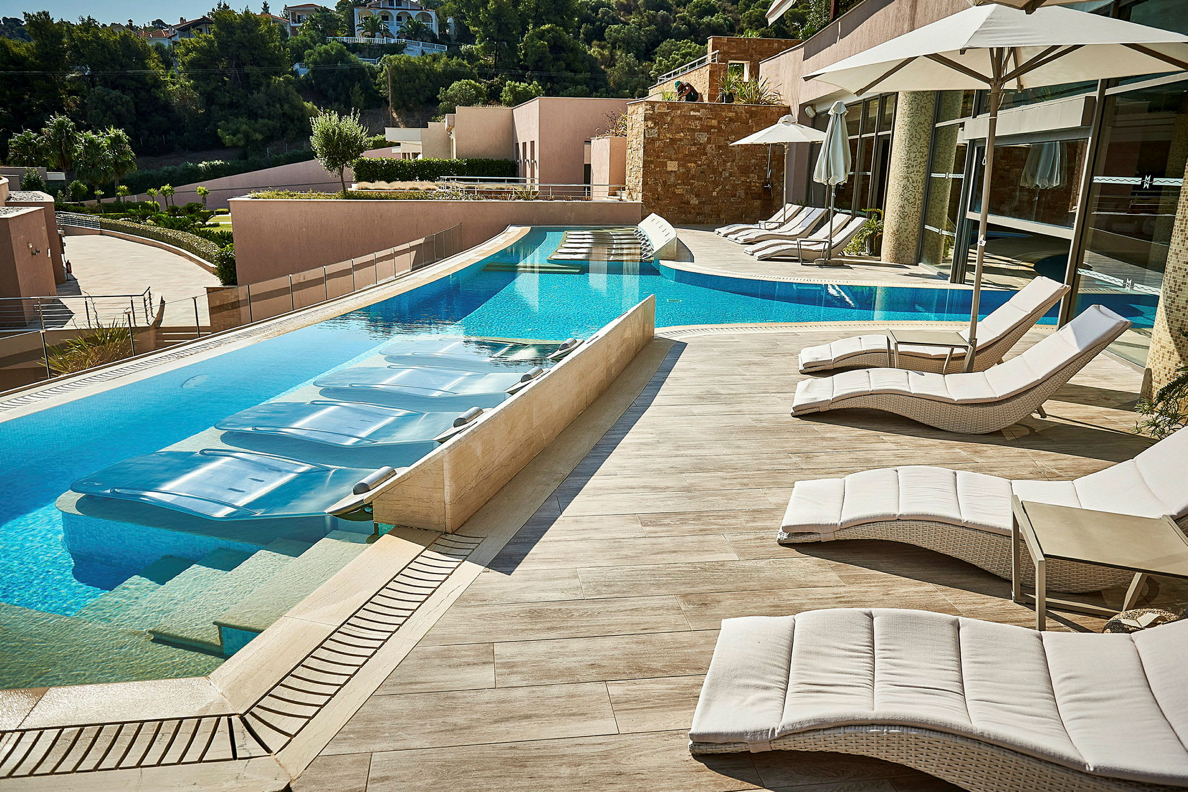 Liggestole og parasoller ved en pool på en hotelterrasse. (AI-genereret tekst)
