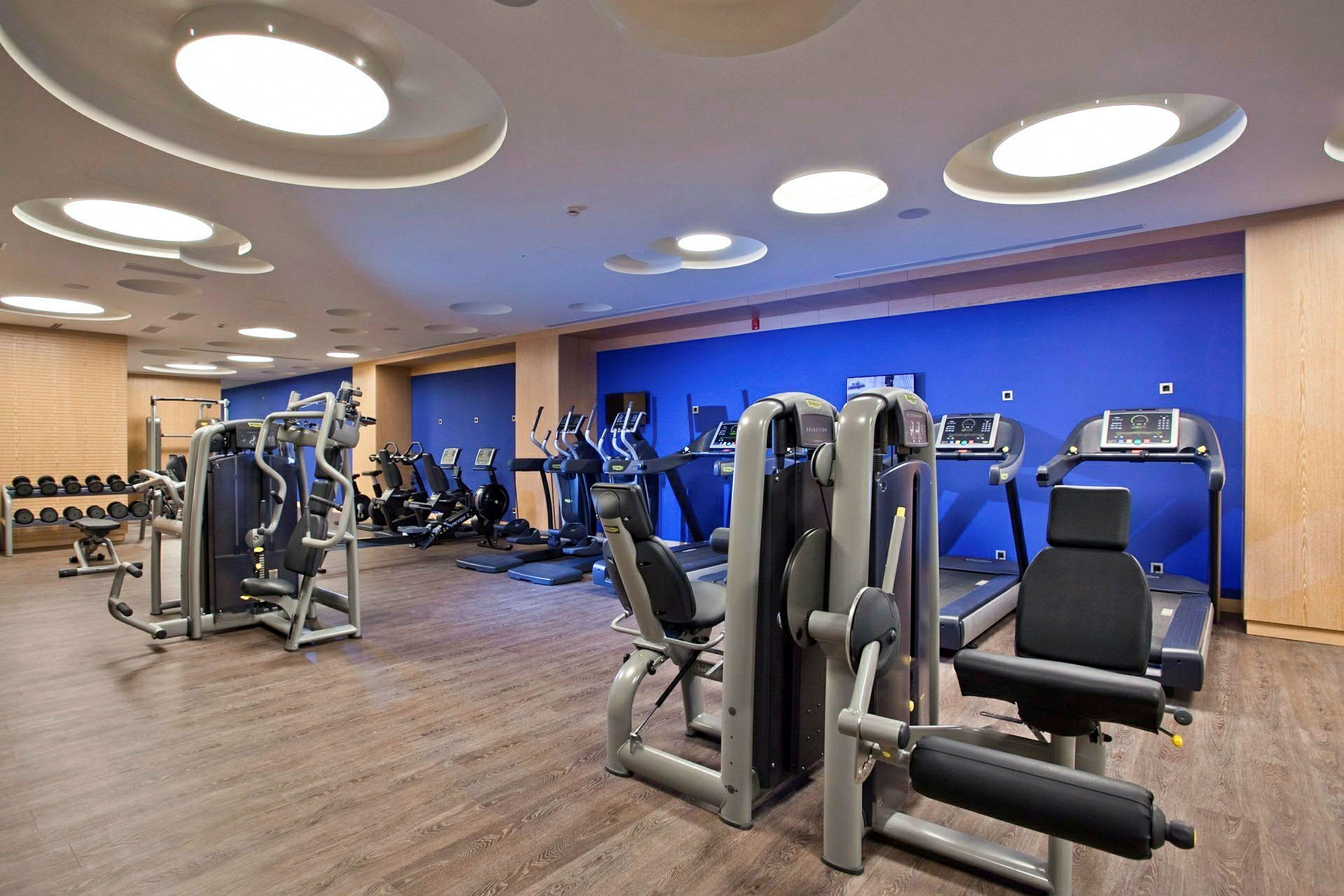 Et moderne fitnesscenter med træningsmaskiner, løbebånd og vægte. (AI-genereret tekst)