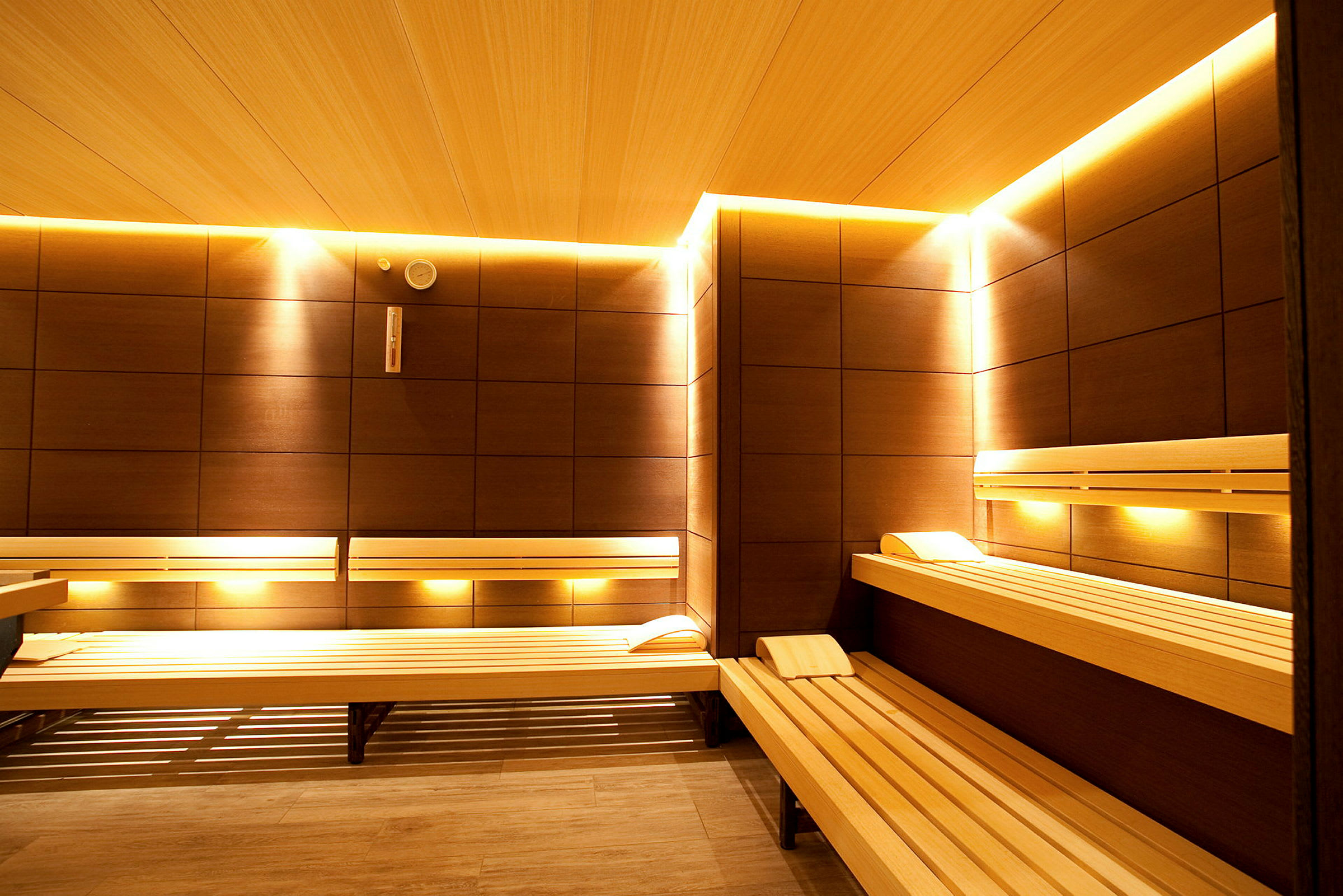 Et interiørbillede af en sauna med træpaneler og belysning langs væggene. (AI-genereret tekst)