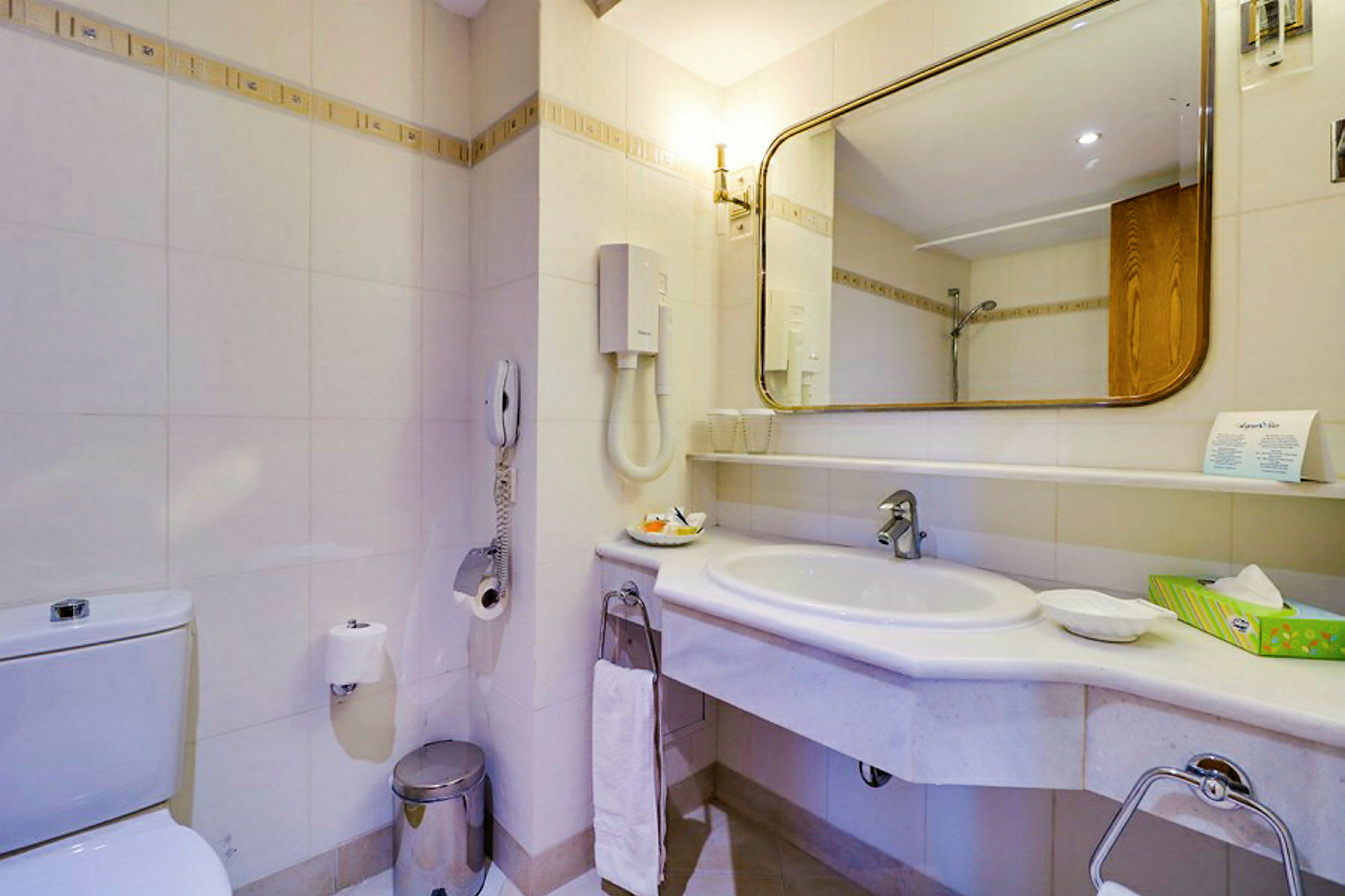 Et badeværelse med håndvask, spejl og toilet. (AI-genereret tekst)