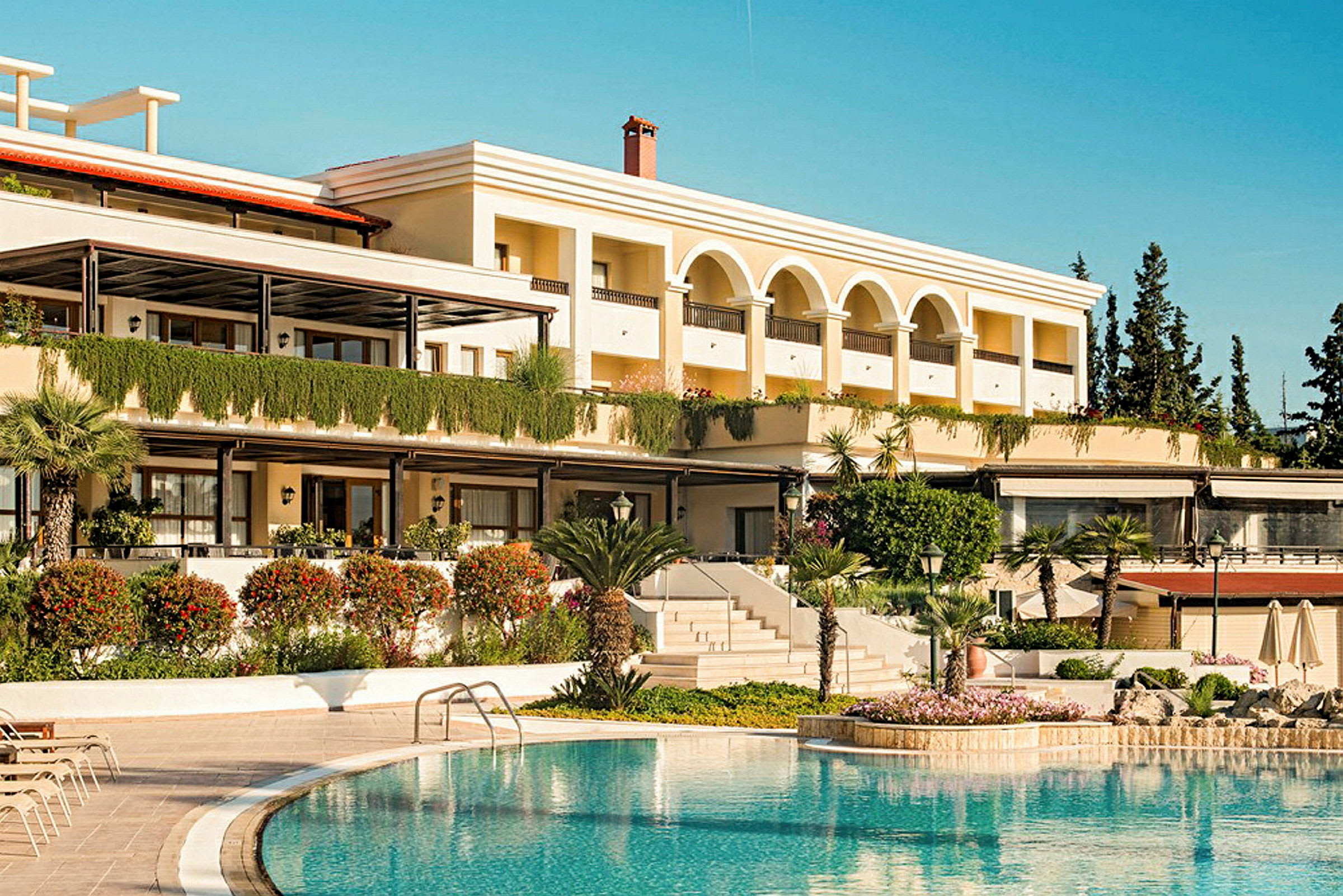 Billede af en hotellbygning med pool i forgrunden. (AI-genereret tekst)