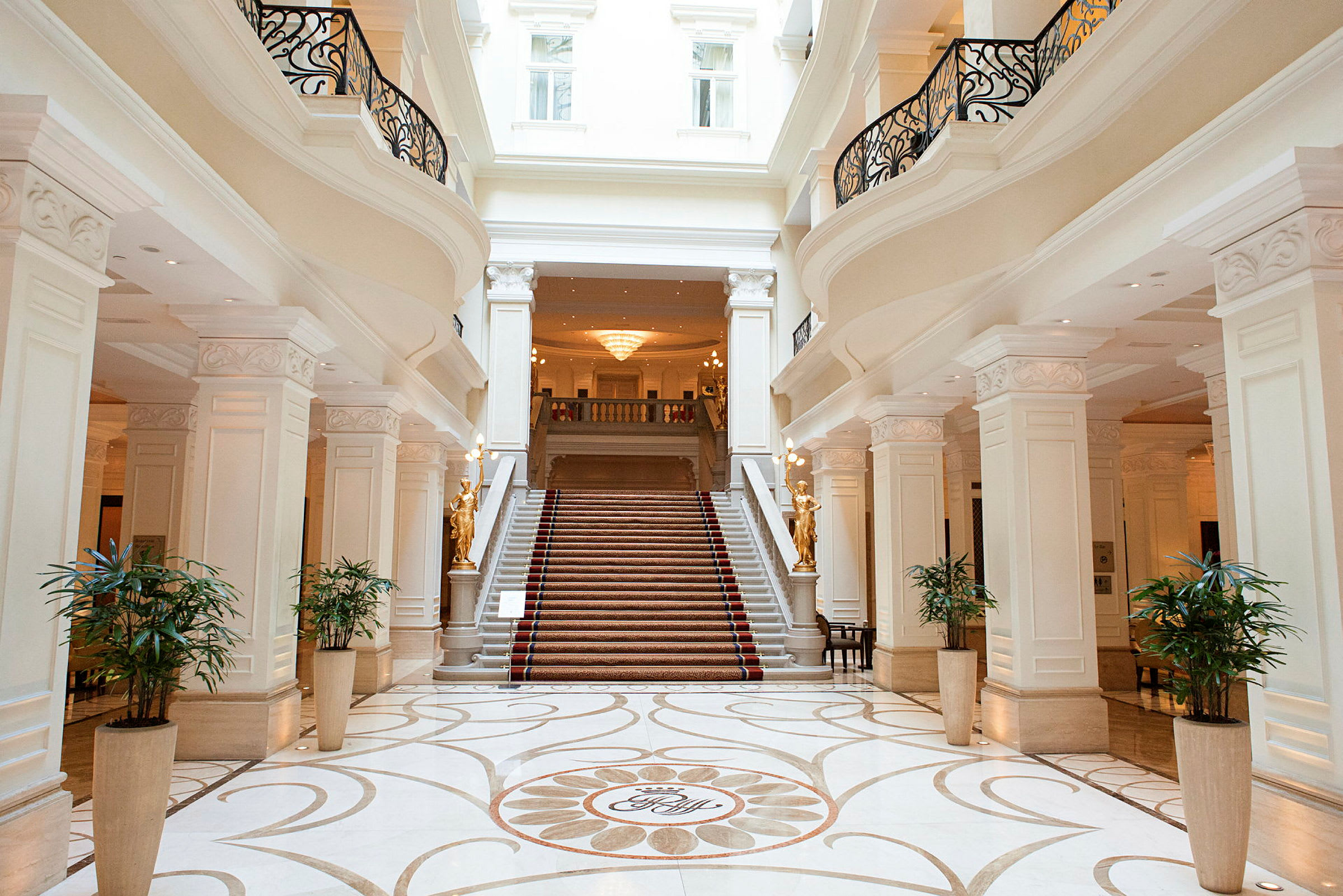 En elegant hotellobby med en bred trappel og dekorerede søjler. (AI-genereret tekst)