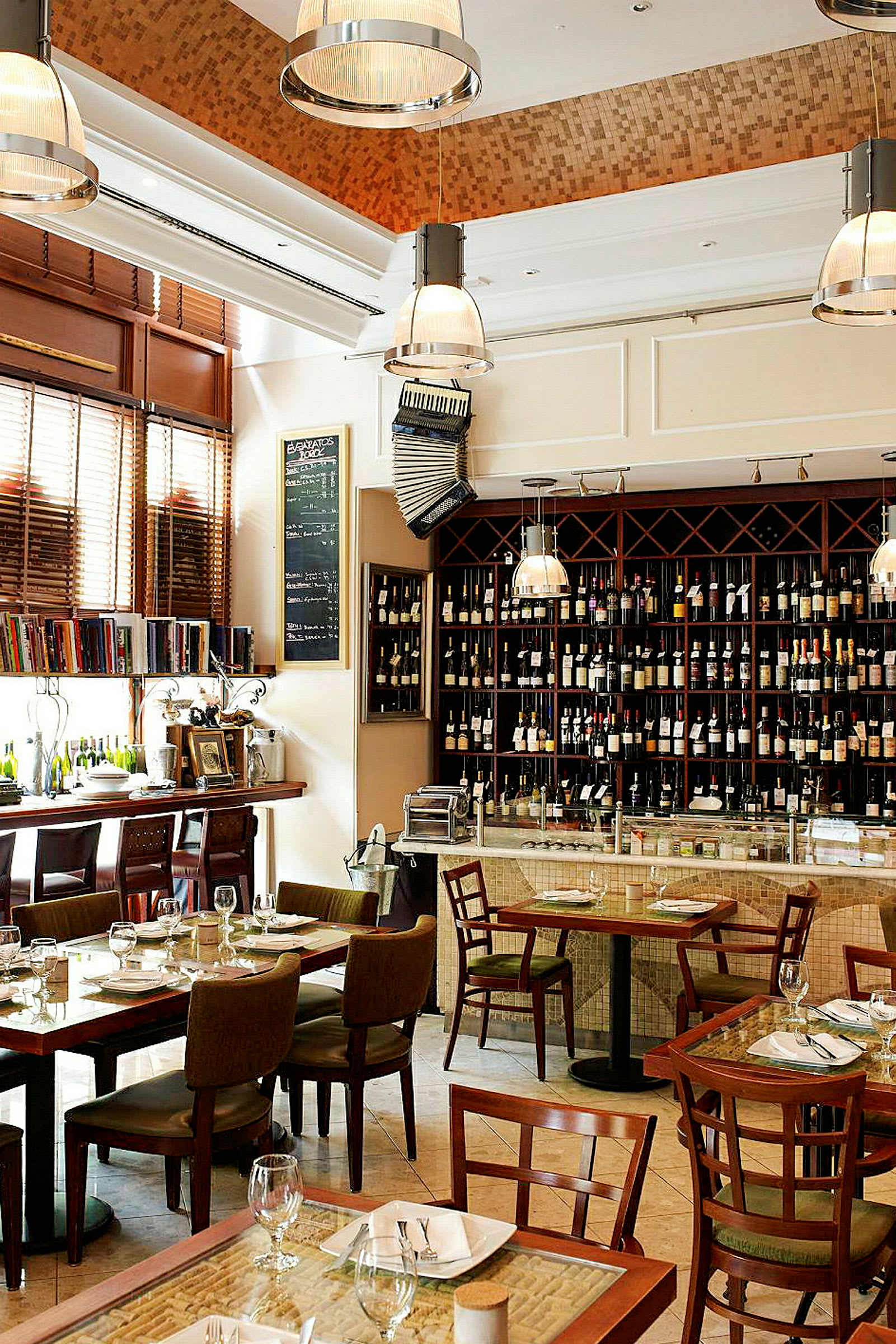Interiør af en restaurant med spiseborde og stole, en hylde med vinflasker og en bardisk. (AI-genereret tekst)
