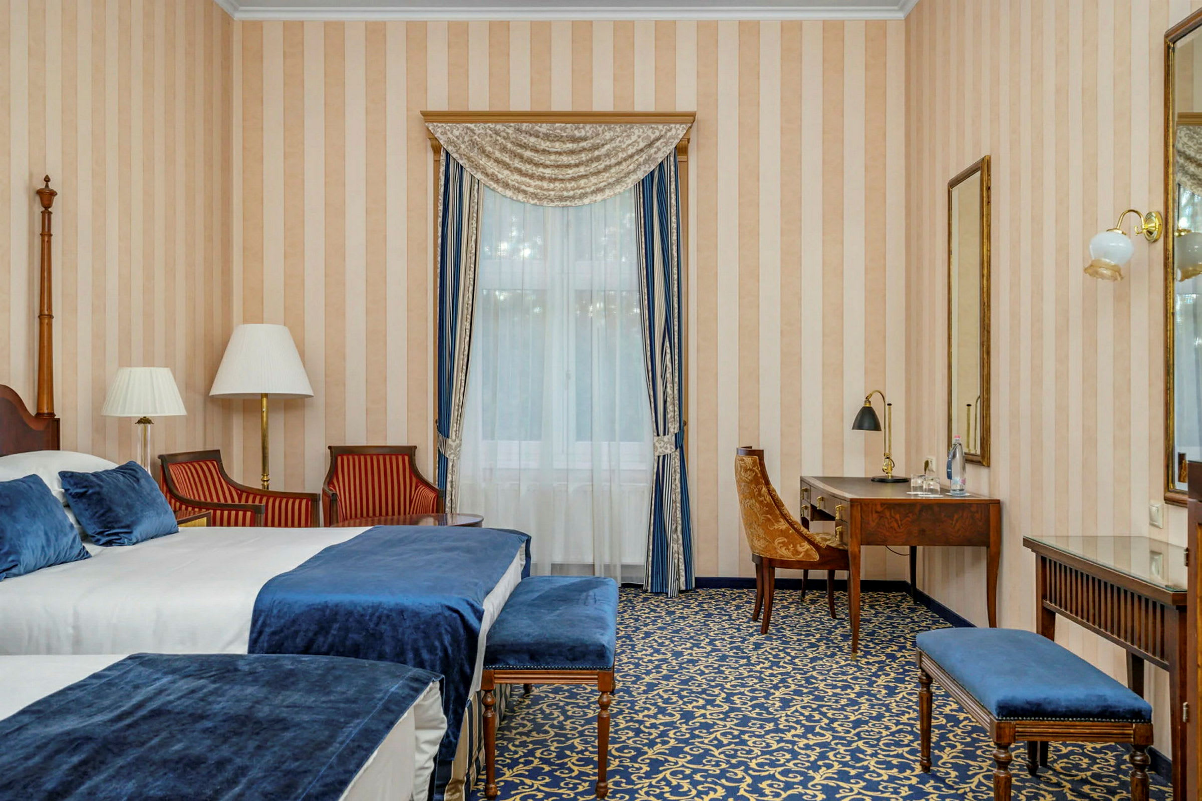 Hotelværelse med senge, skrivebord og siddepladser. (AI-genereret tekst)