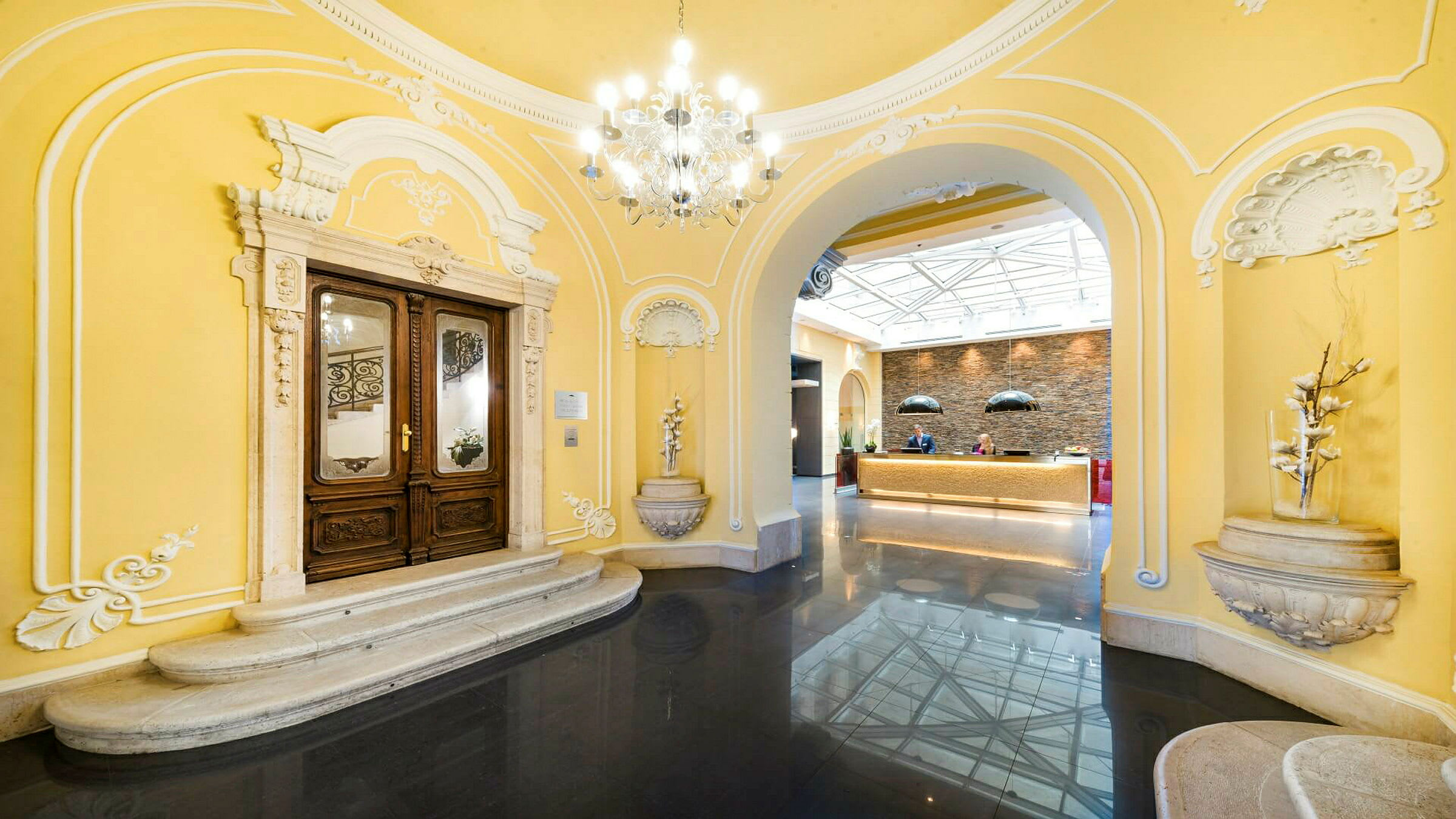 Indgangsområde med klassiske arkitektoniske detaljer og reception i en lys atmosfære. (AI-genereret tekst)