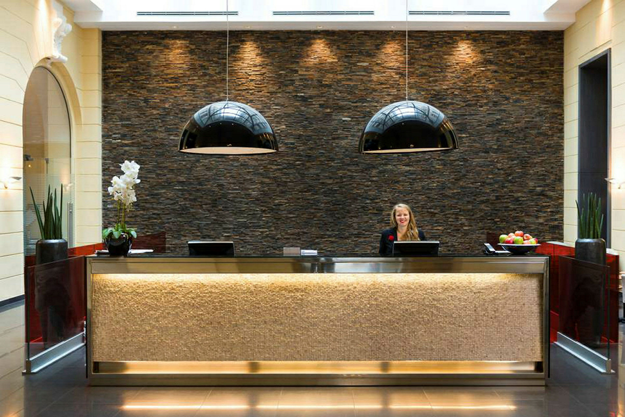 Hotellets reception med dekorativ stenmur og moderne belysning. (AI-genereret tekst)