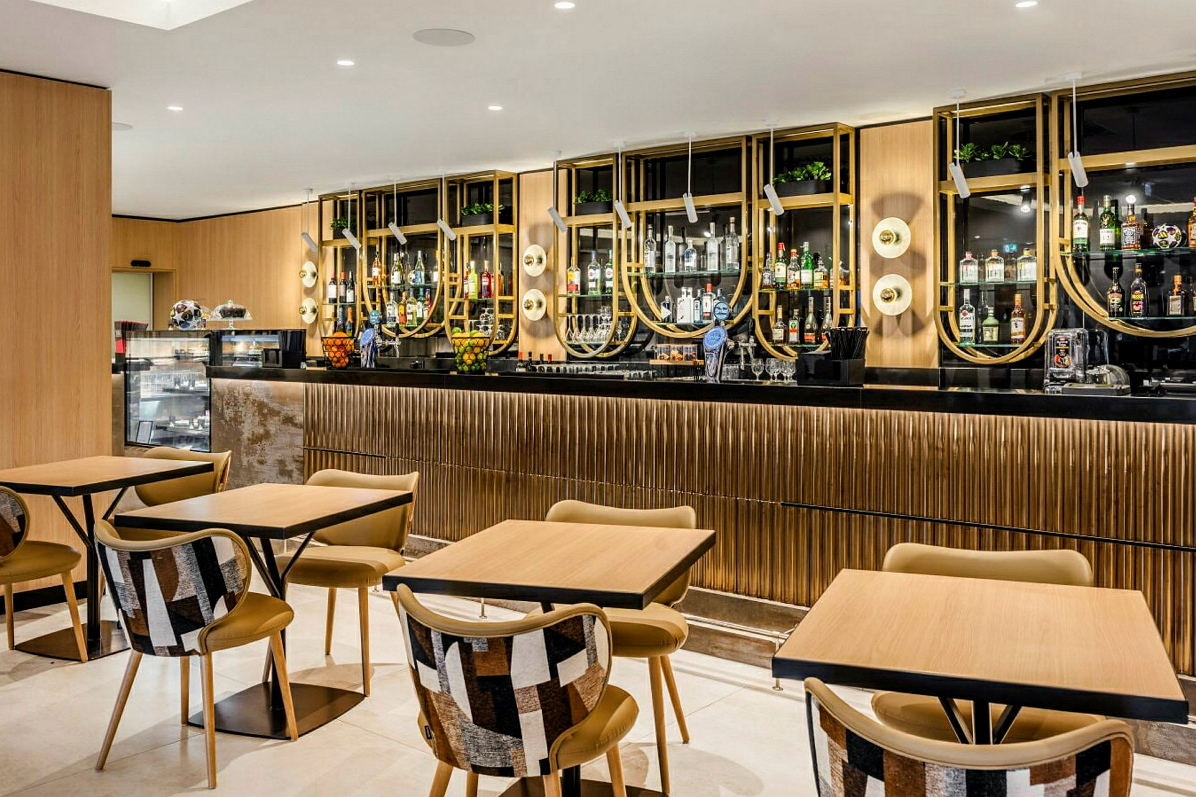 En moderne bar og café med stilfulde borde og stole samt en elegant og velorganiseret cocktailhylde i baggrunden. (AI-genereret tekst)