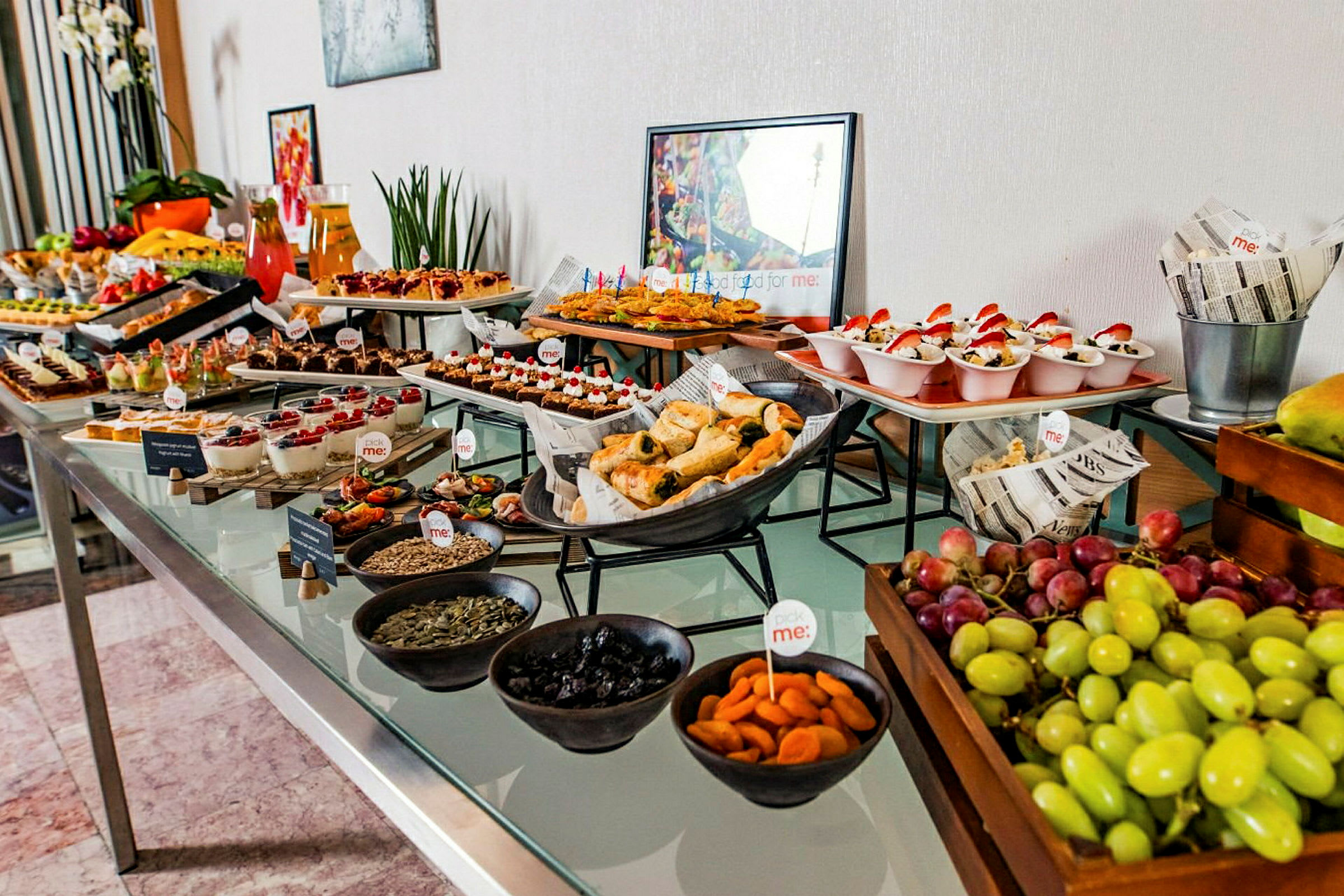 Et buffetbord med forskellige retter og snacks, inklusive frugt, bagværk og desserter. (AI-genereret tekst)
