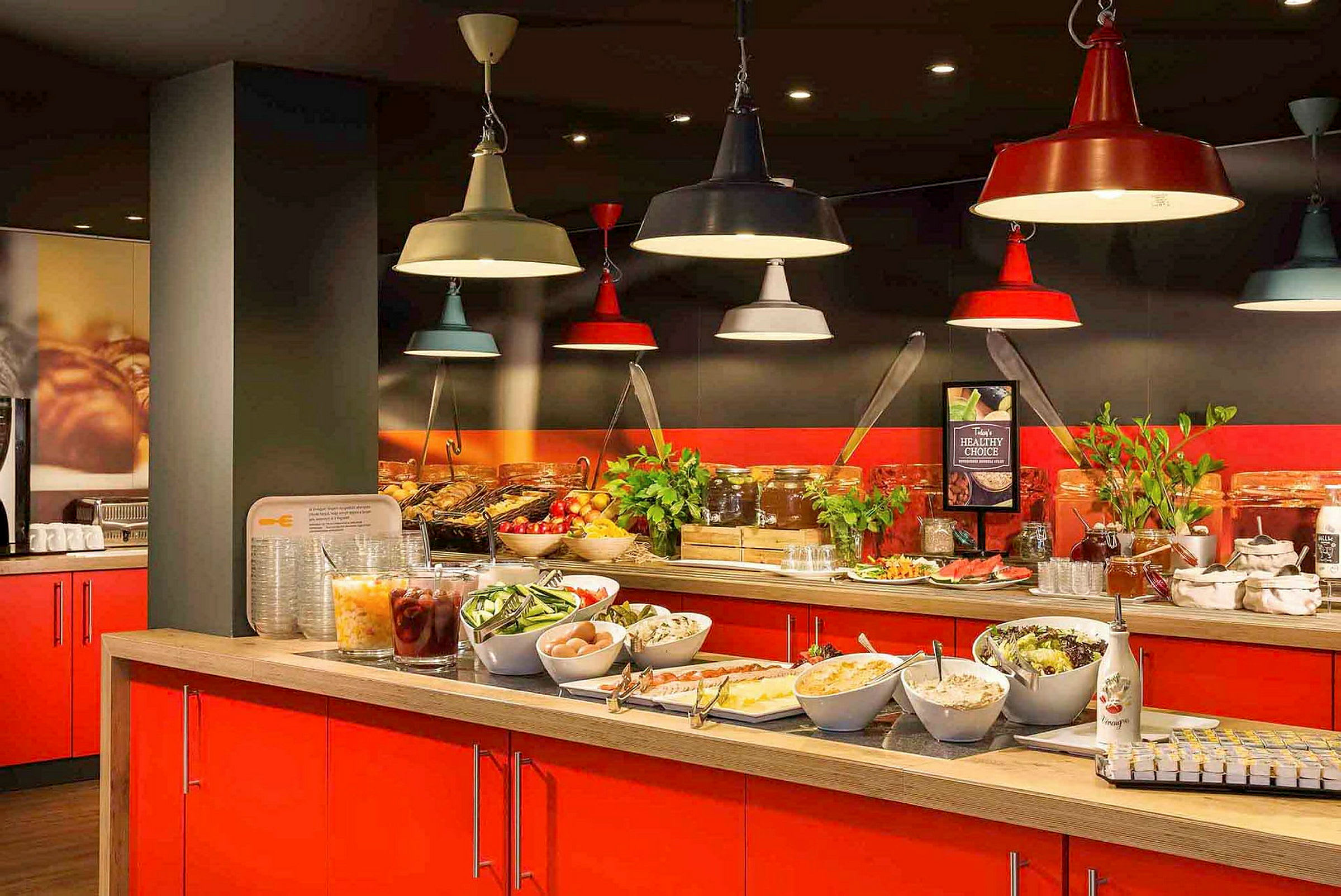 Buffetbord med salater, frugt og tilbehør, placeret under farverige lamper. (AI-genereret tekst)