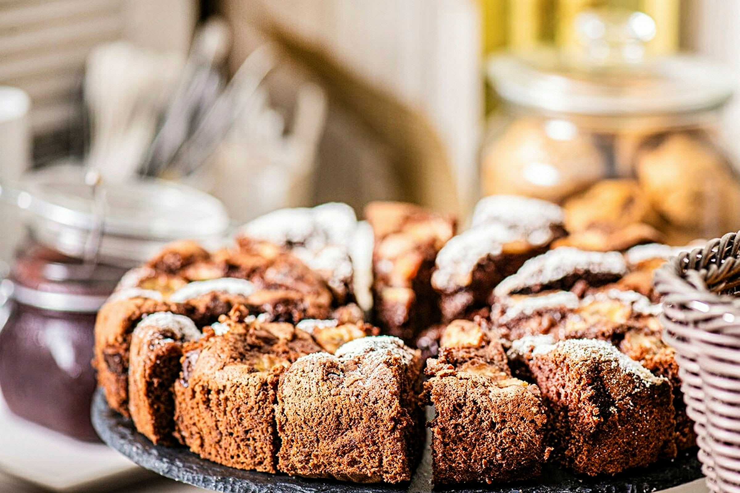 En rund chokoladekage skåret i stykker, serveret på et fad. (AI-genereret tekst)