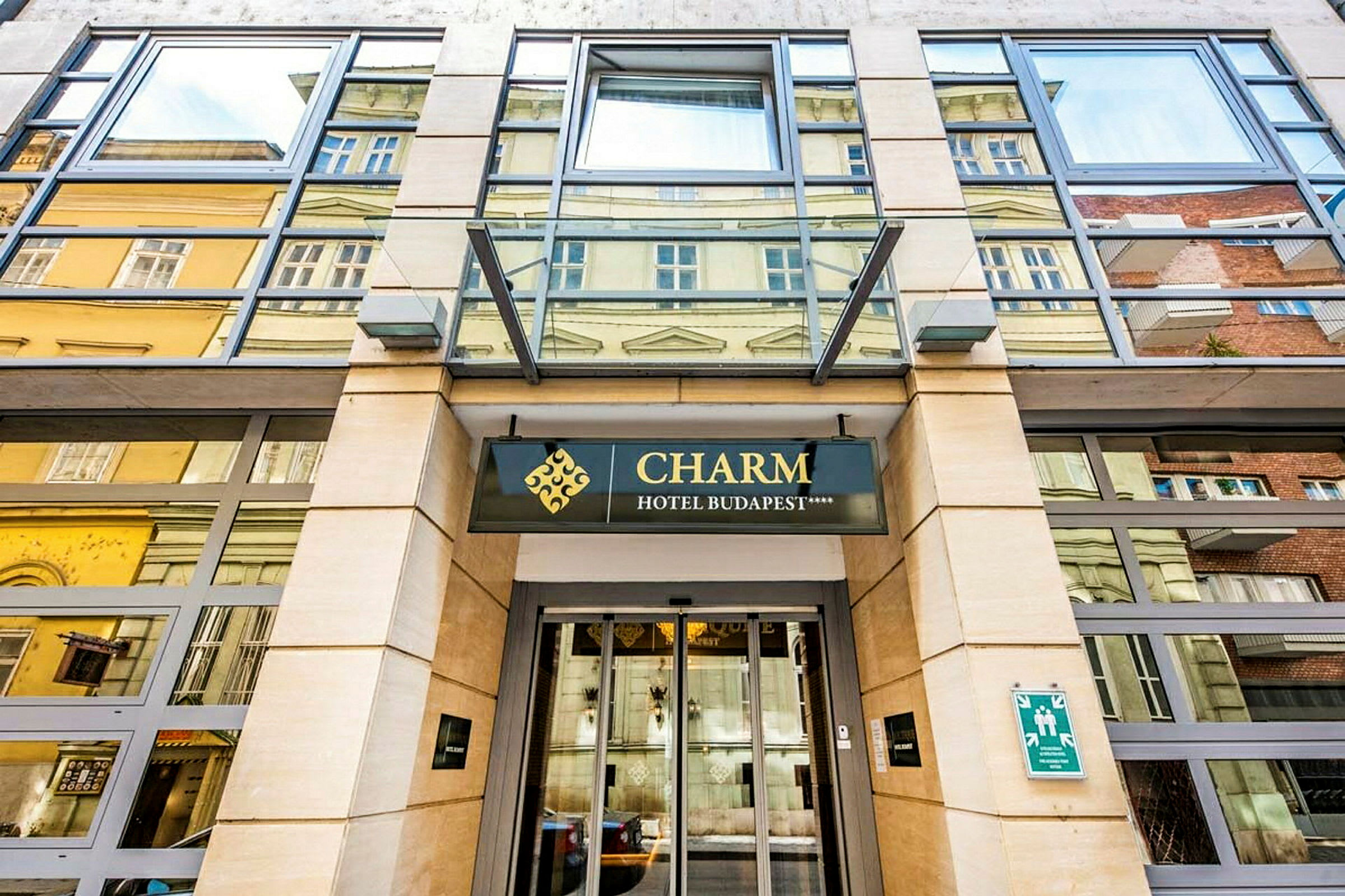 Indgangen til et hotel med skiltet "Charm Hotel Budapest". (AI-genereret tekst)
