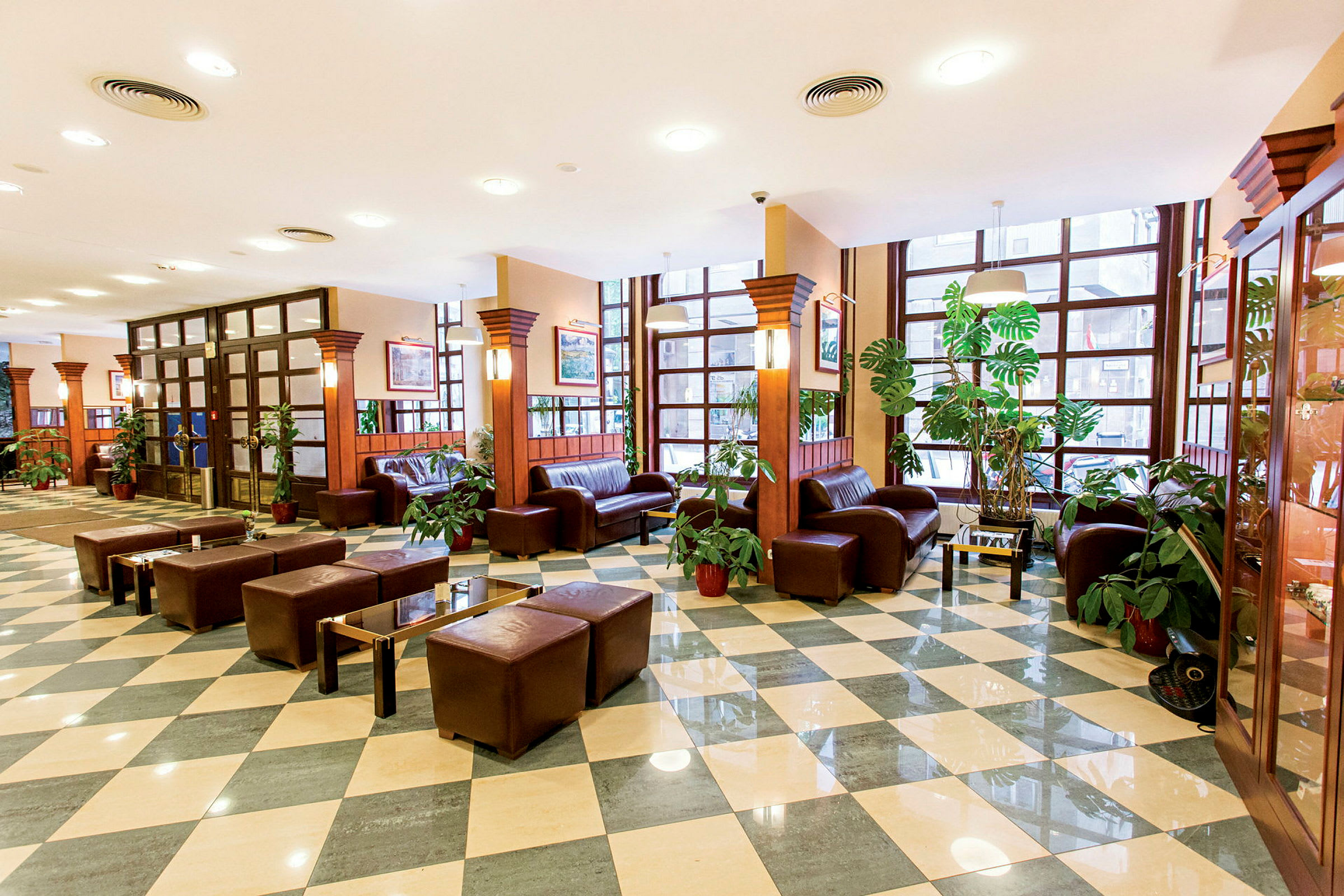 Hotellets lobby med brune lædermøbler og grønne planter. (AI-genereret tekst)