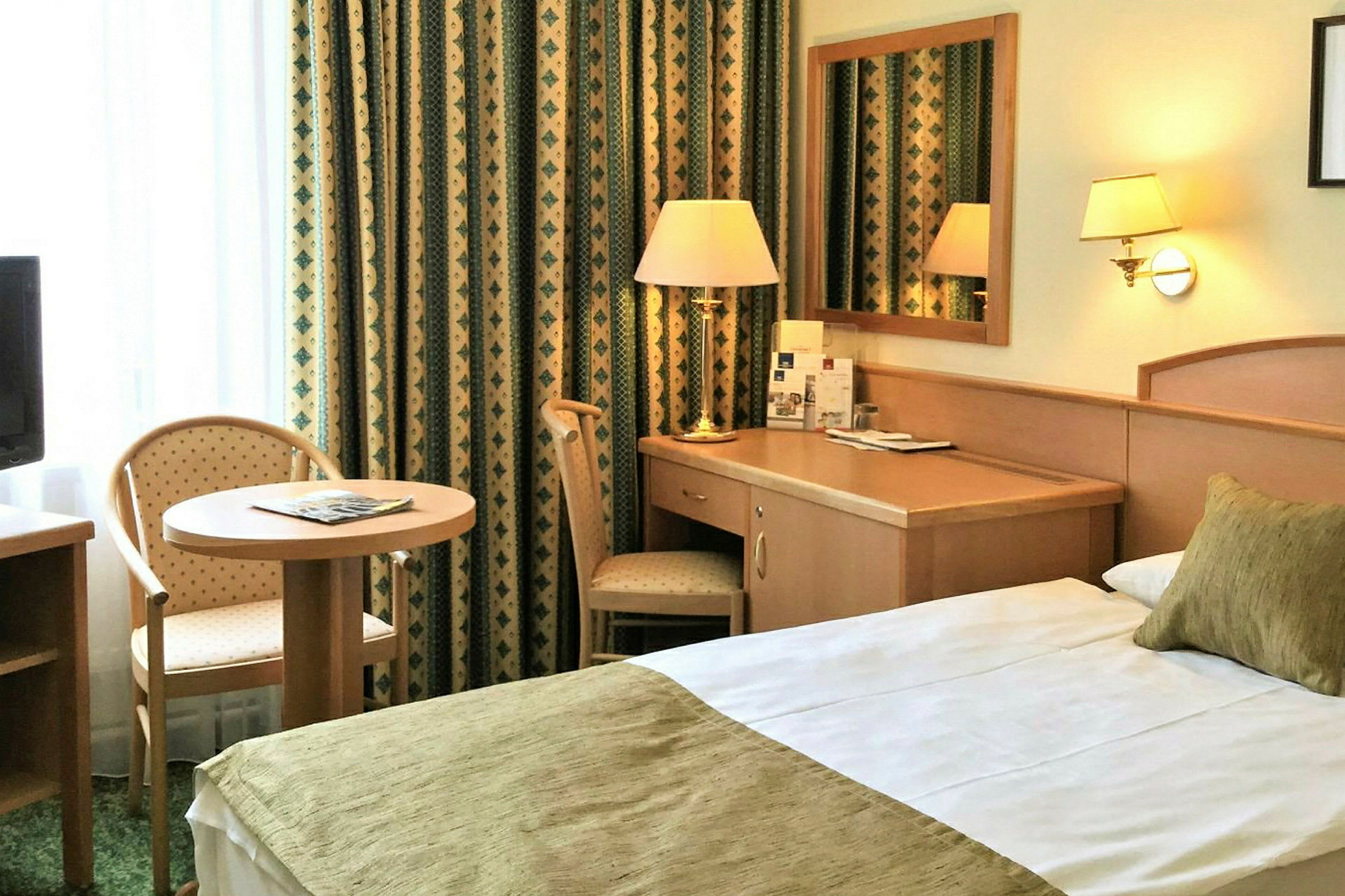Hotelværelse med seng, skrivebord og siddeplads ved et lille bord. (AI-genereret tekst)