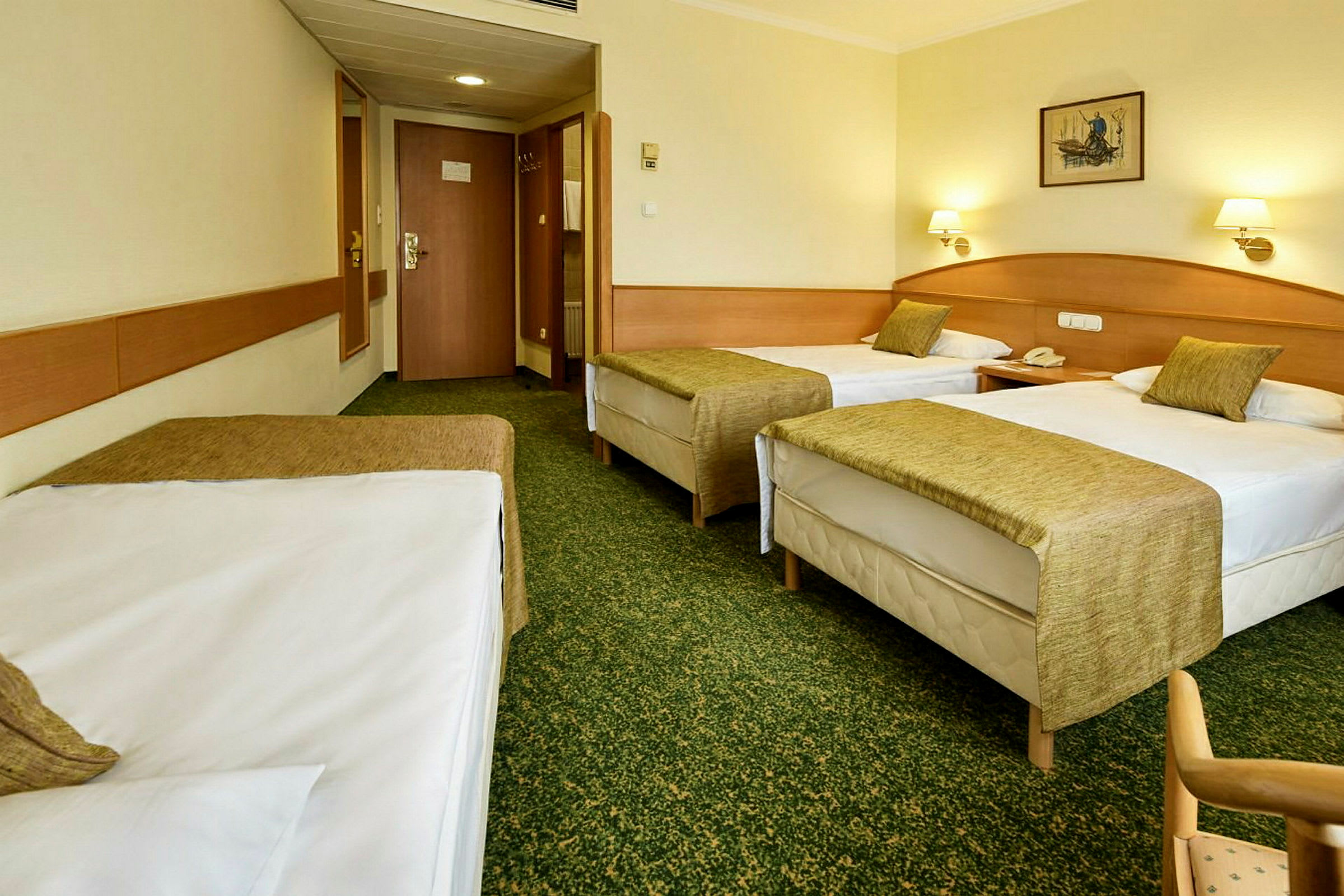Hotelværelse med tre enkeltsenge, grønne sengetæpper og lyse vægge. (AI-genereret tekst)
