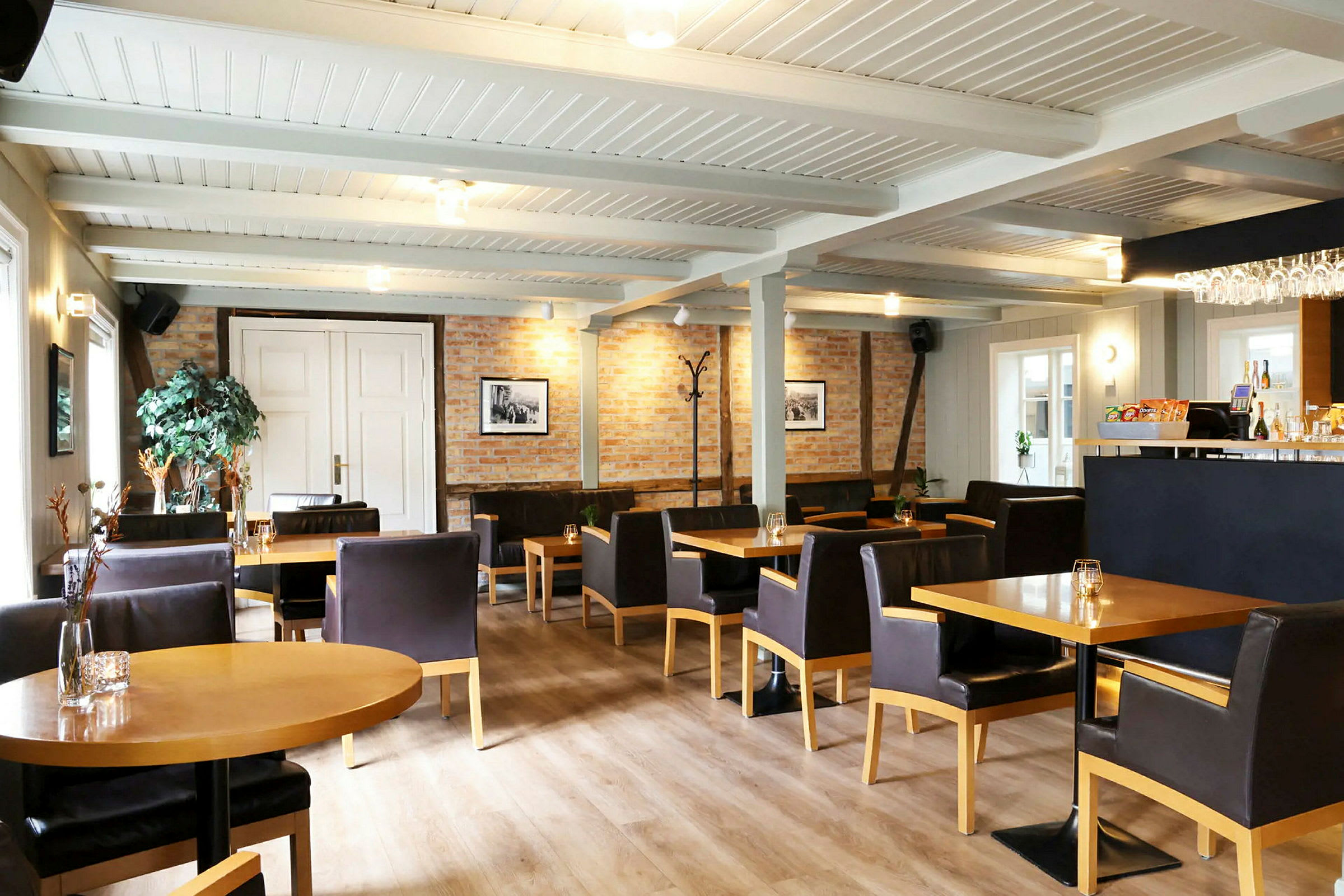 Et billede af en indendørs restaurant med borde, stole og en bar. (AI-genereret tekst)