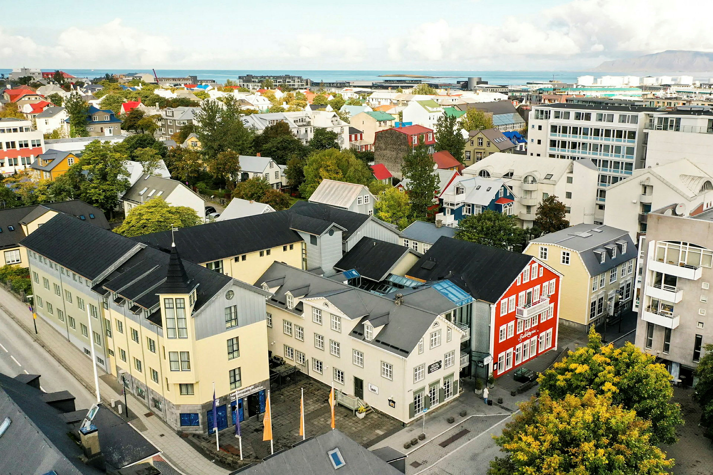Luftfoto af en by med farverige bygninger og grønt. (AI-genereret tekst)